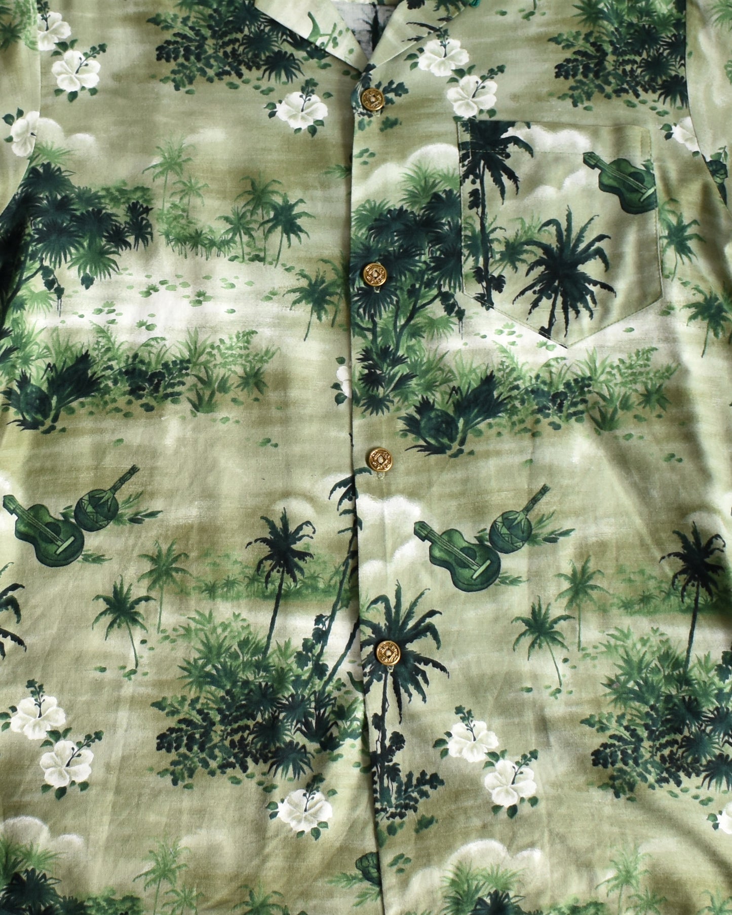 close up of the tropical print on a vintage 1950s green Hawaiian shirt by Royal Hawaiian on a white background