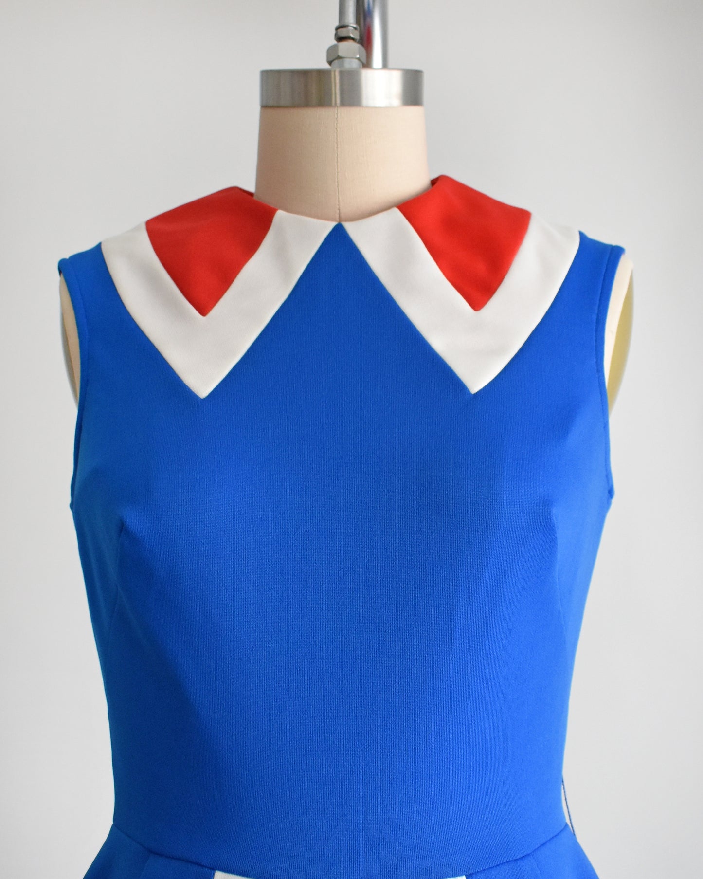 close up of the patterned collar on a vintage 60s/70s blue and red mod mini dress on a mannequin against a white background