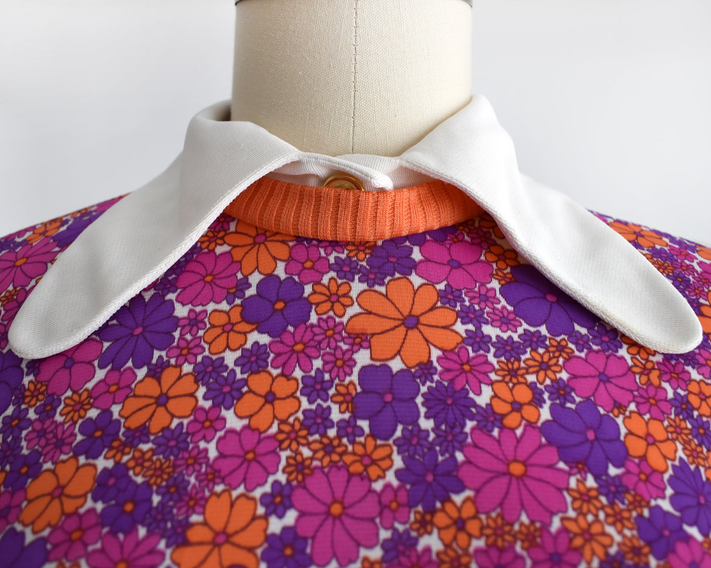 close up of the floral-patterned bodice that has a white collar, orange trim, and decorative button
