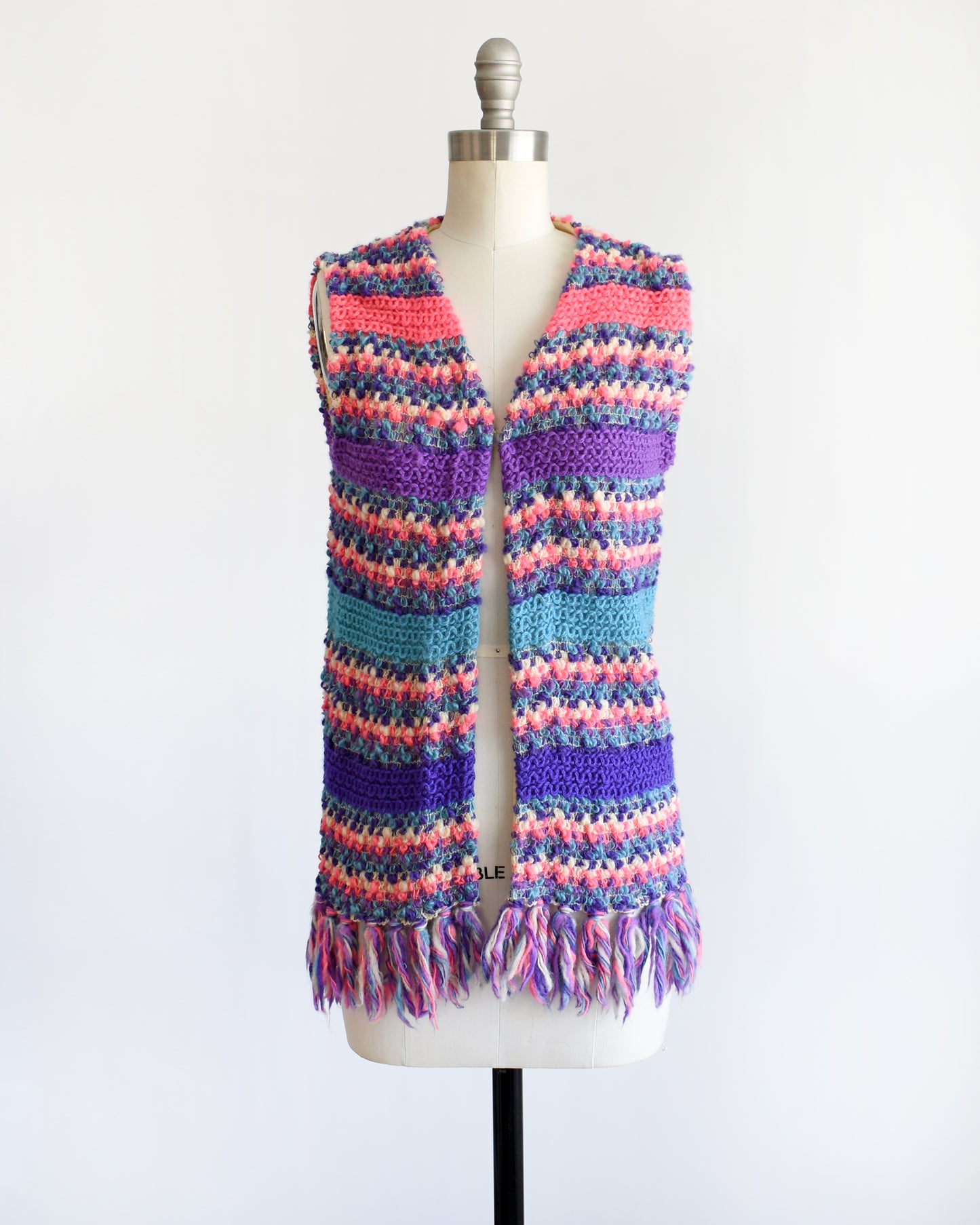 a vintage 1960s/1970s multicolored striped crochet vest on a mannequin against a white background