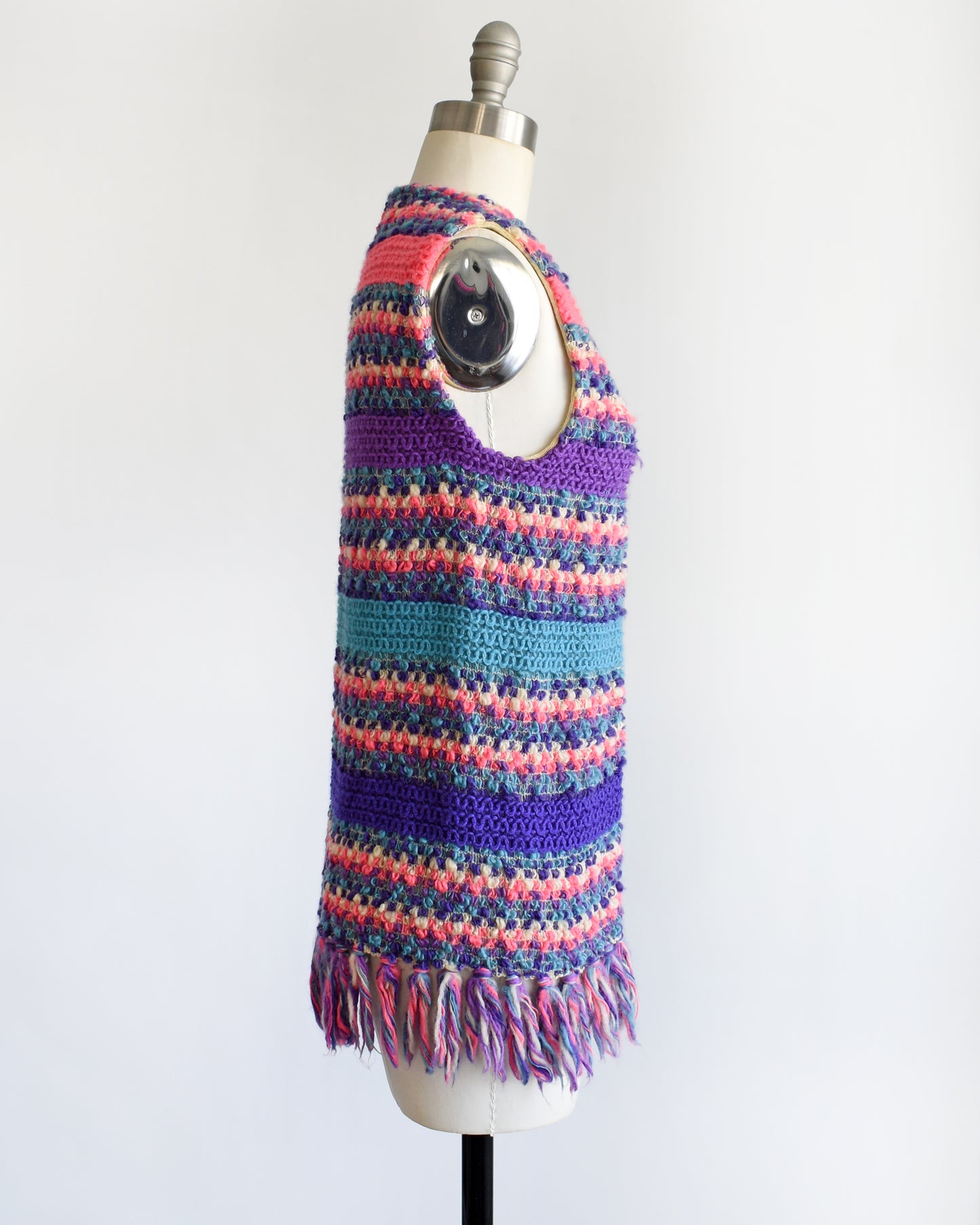 side view of a vintage 1960s/1970s multicolored striped crochet vest on a mannequin against a white background