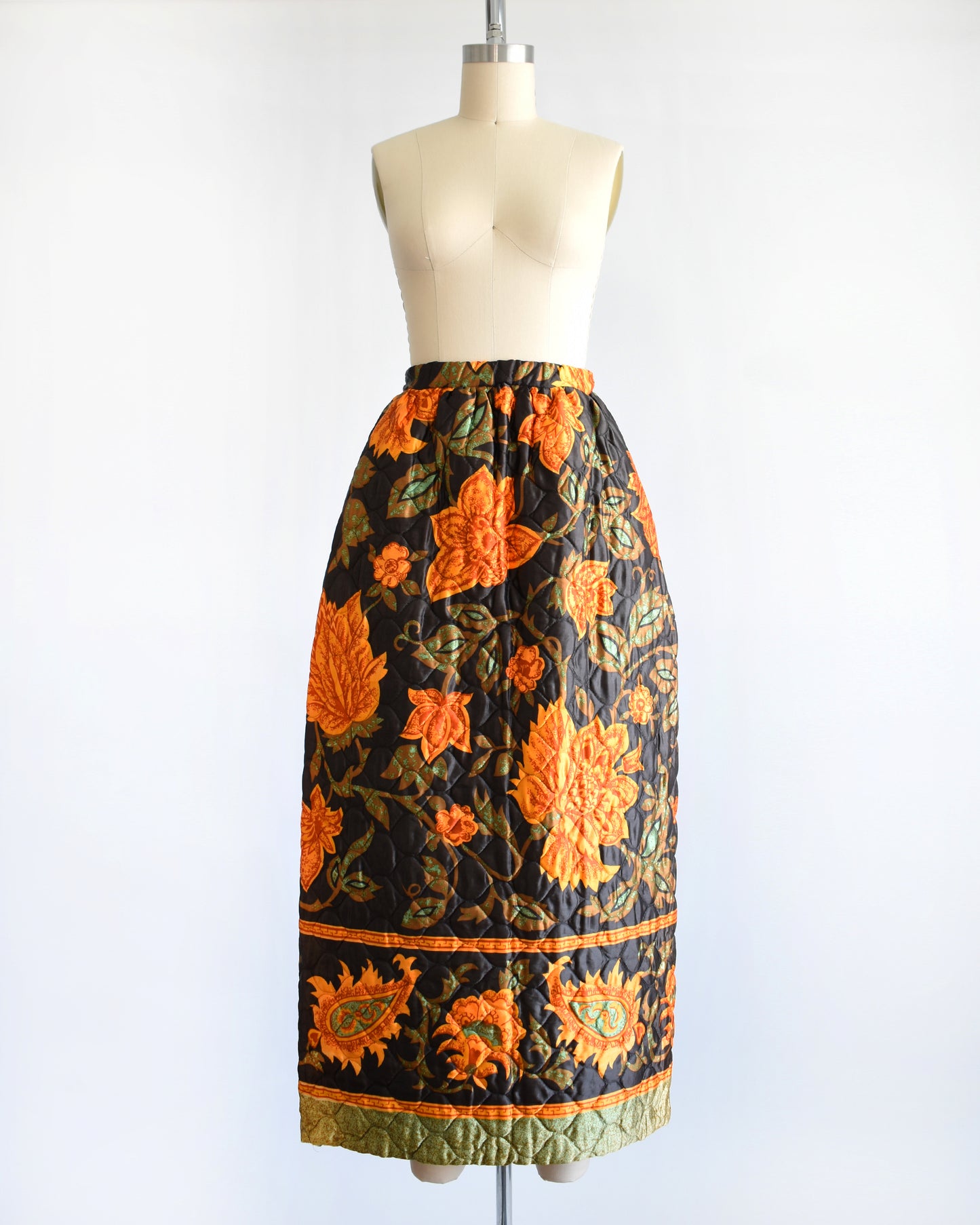 a vintage 1970s dark brown and orange floral patterned maxi skirt on a mannequin against a white background