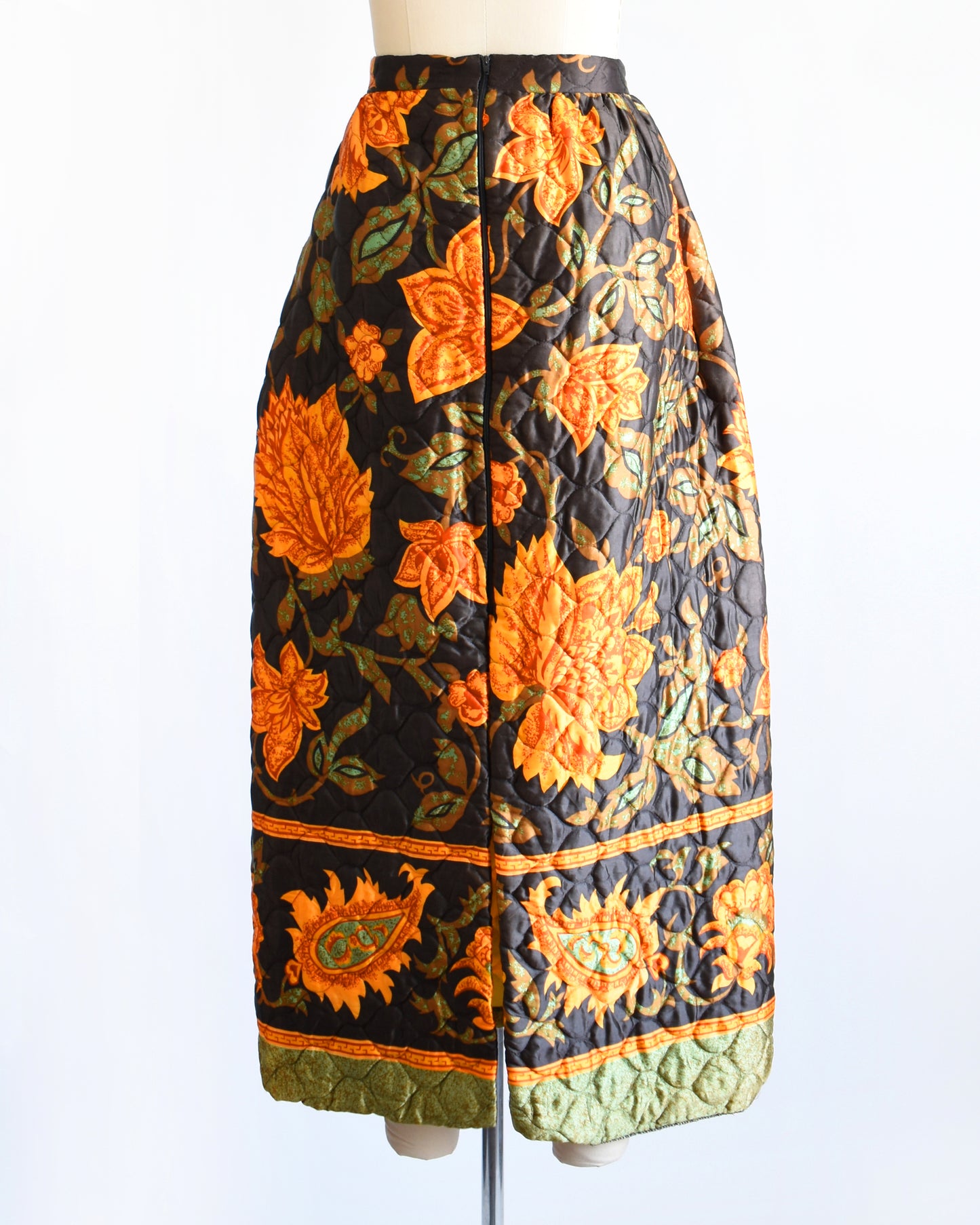 back view of a vintage 1970s dark brown and orange floral patterned maxi skirt on a mannequin against a white background