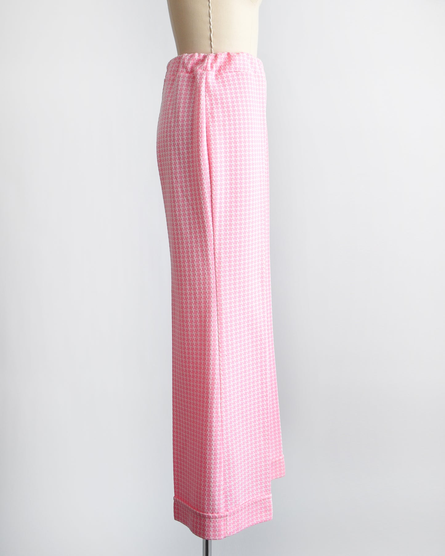 Side view of a vintage 1970s pink  and white houndstooth print wide leg pants on a dress form