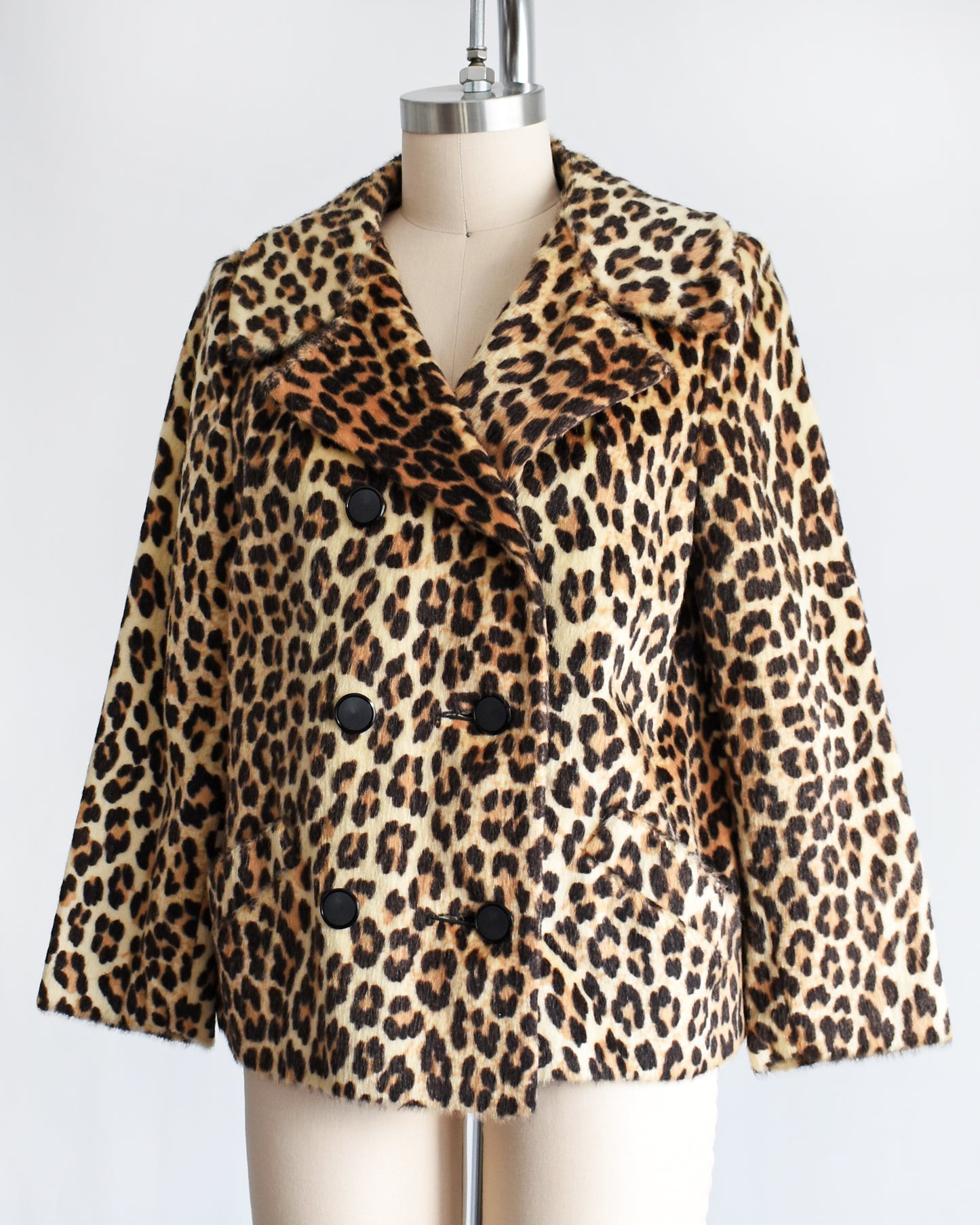 side front view of a vintage 1960s leopard print jacket on a mannequin against a white background