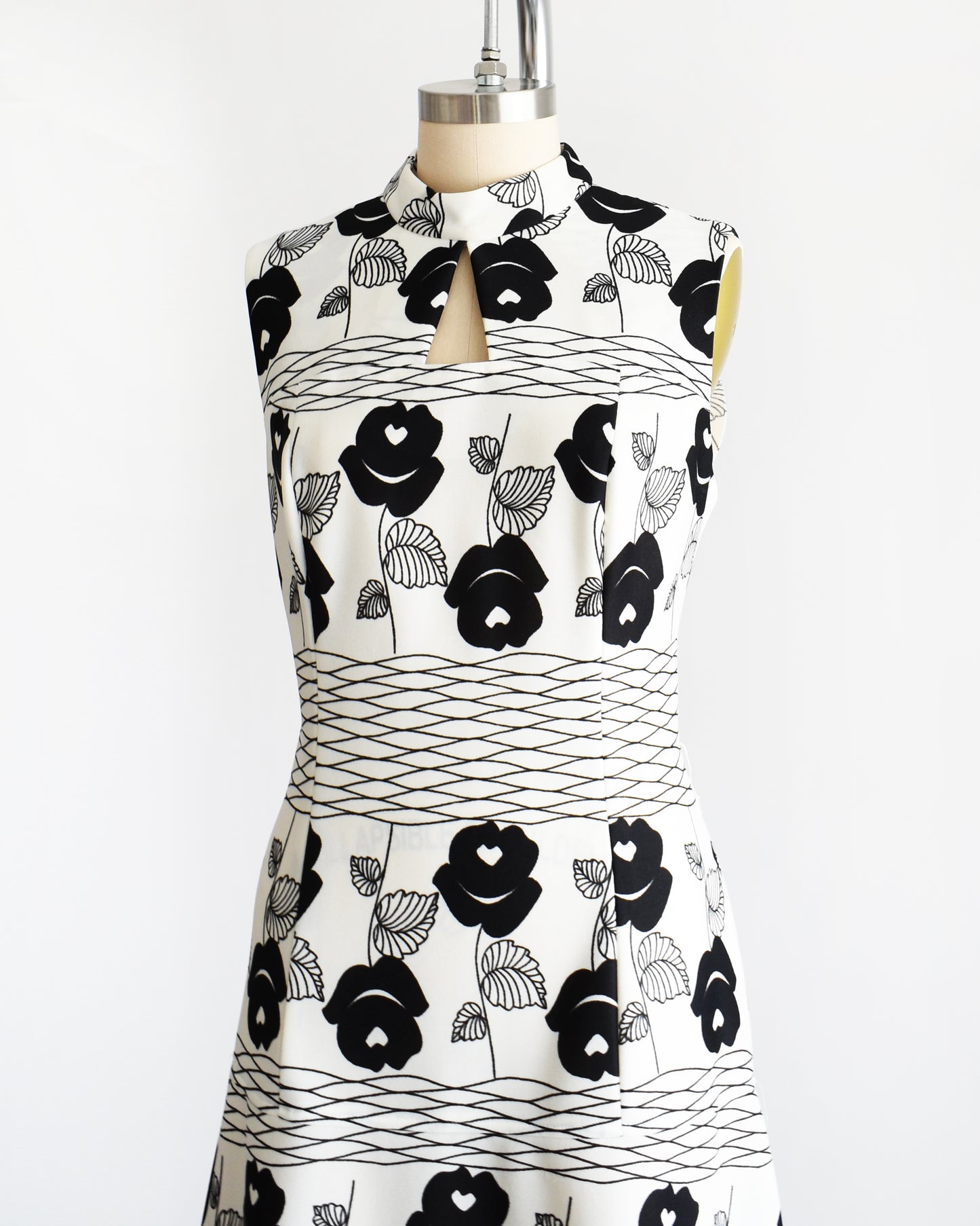 A vintage 70s white maxi dress black floral print with wavy horizontal lines. Dress is shown without the belt.
