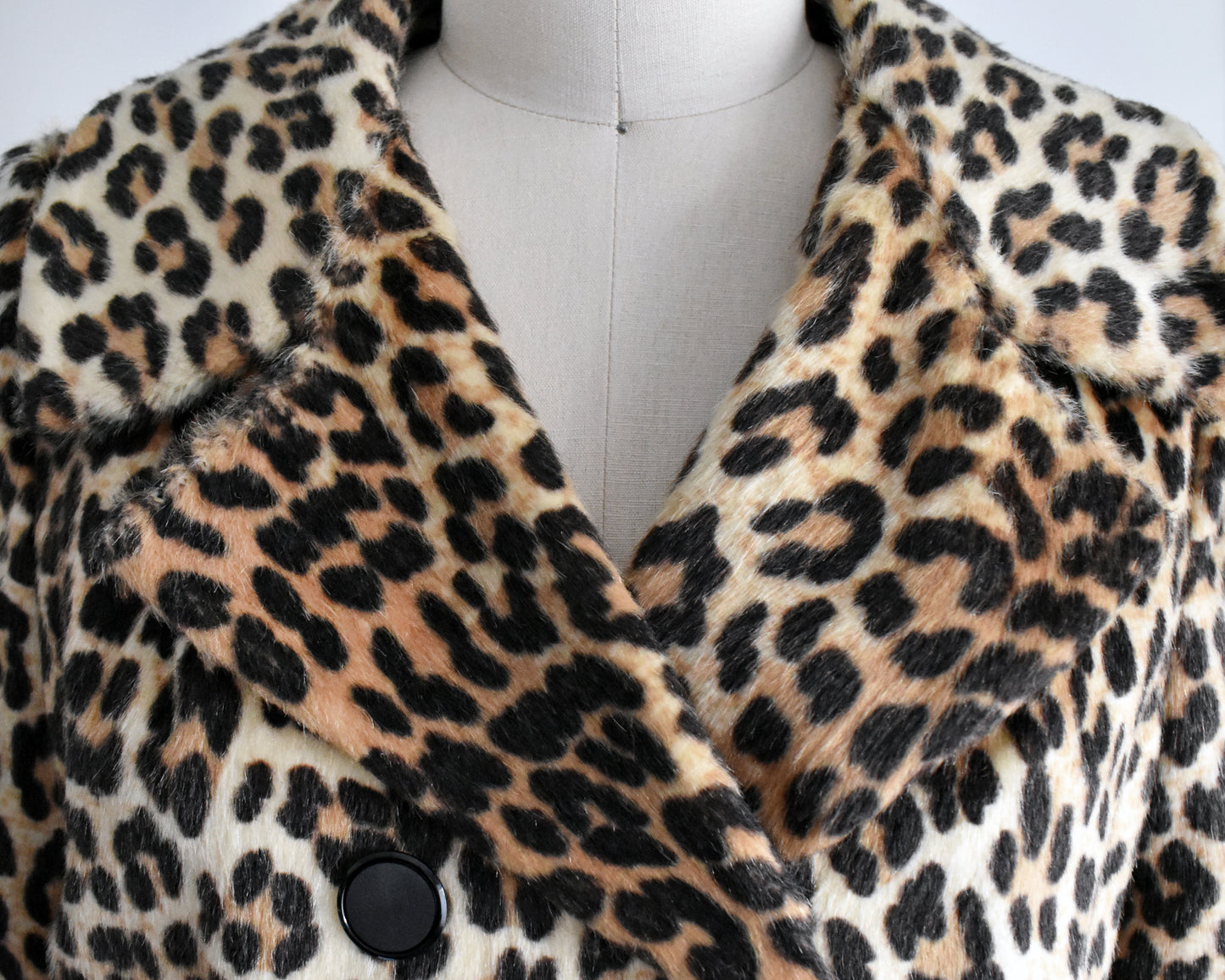 close up of the collar on a vintage 1960s leopard print jacket on a mannequin against a white background