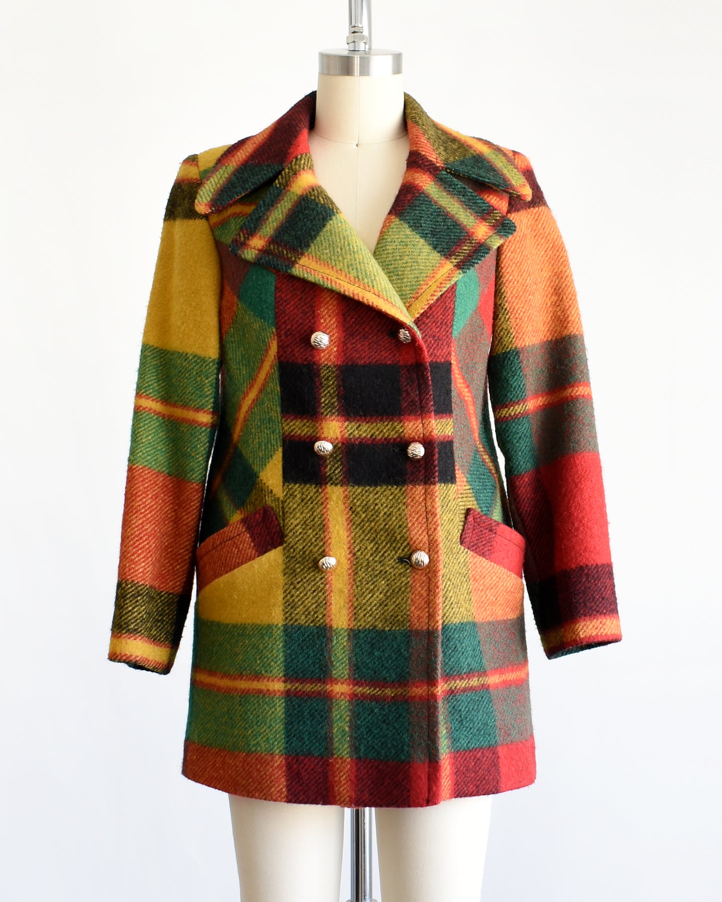 a vintage 1970s rainbow plaid coat on a mannequin against a white background
