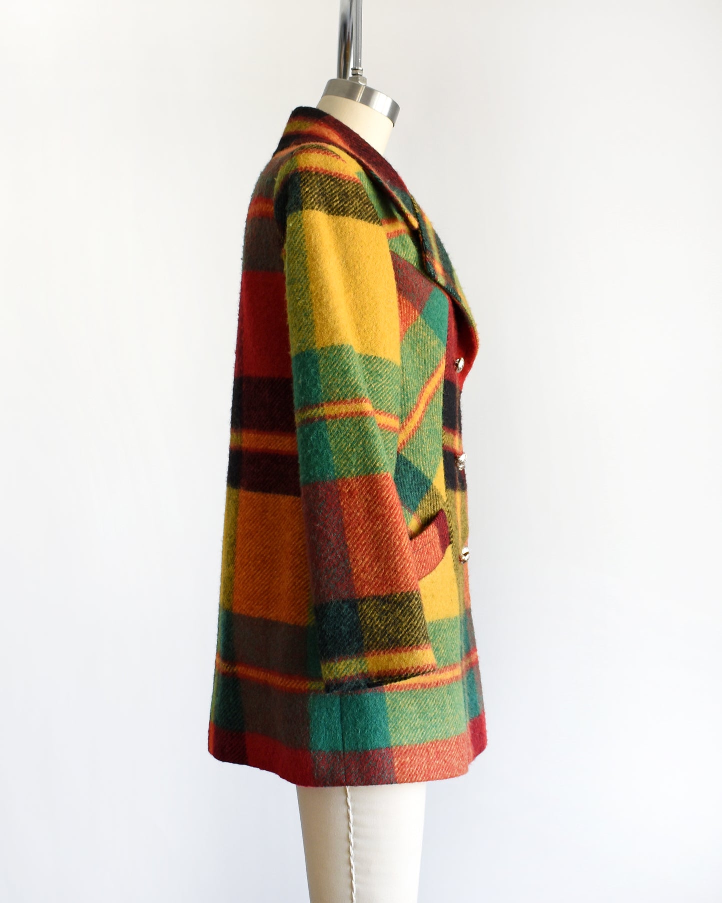 side view of a vintage 1970s rainbow plaid coat on a mannequin against a white background