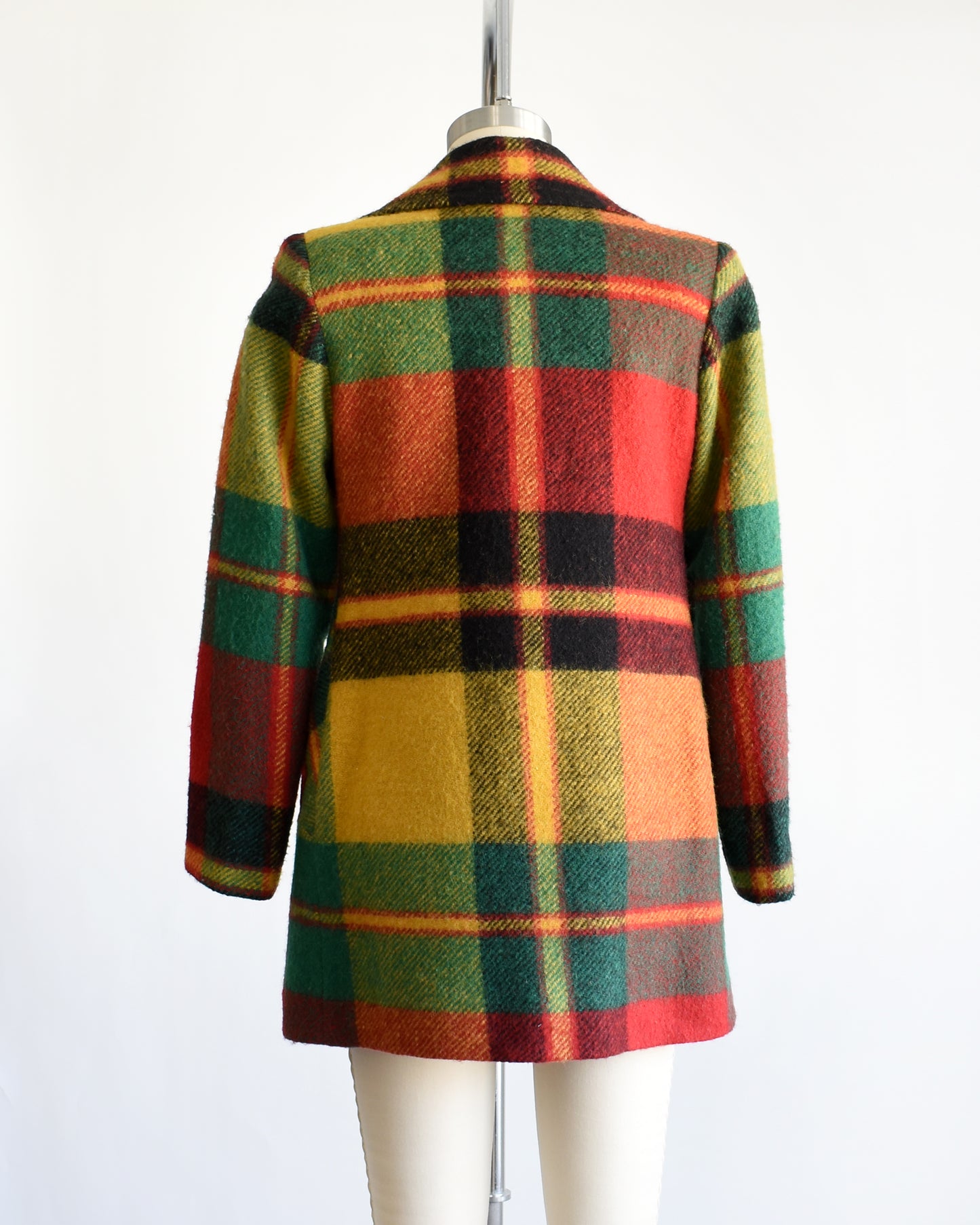 back view of a vintage 1970s rainbow plaid coat on a mannequin against a white background