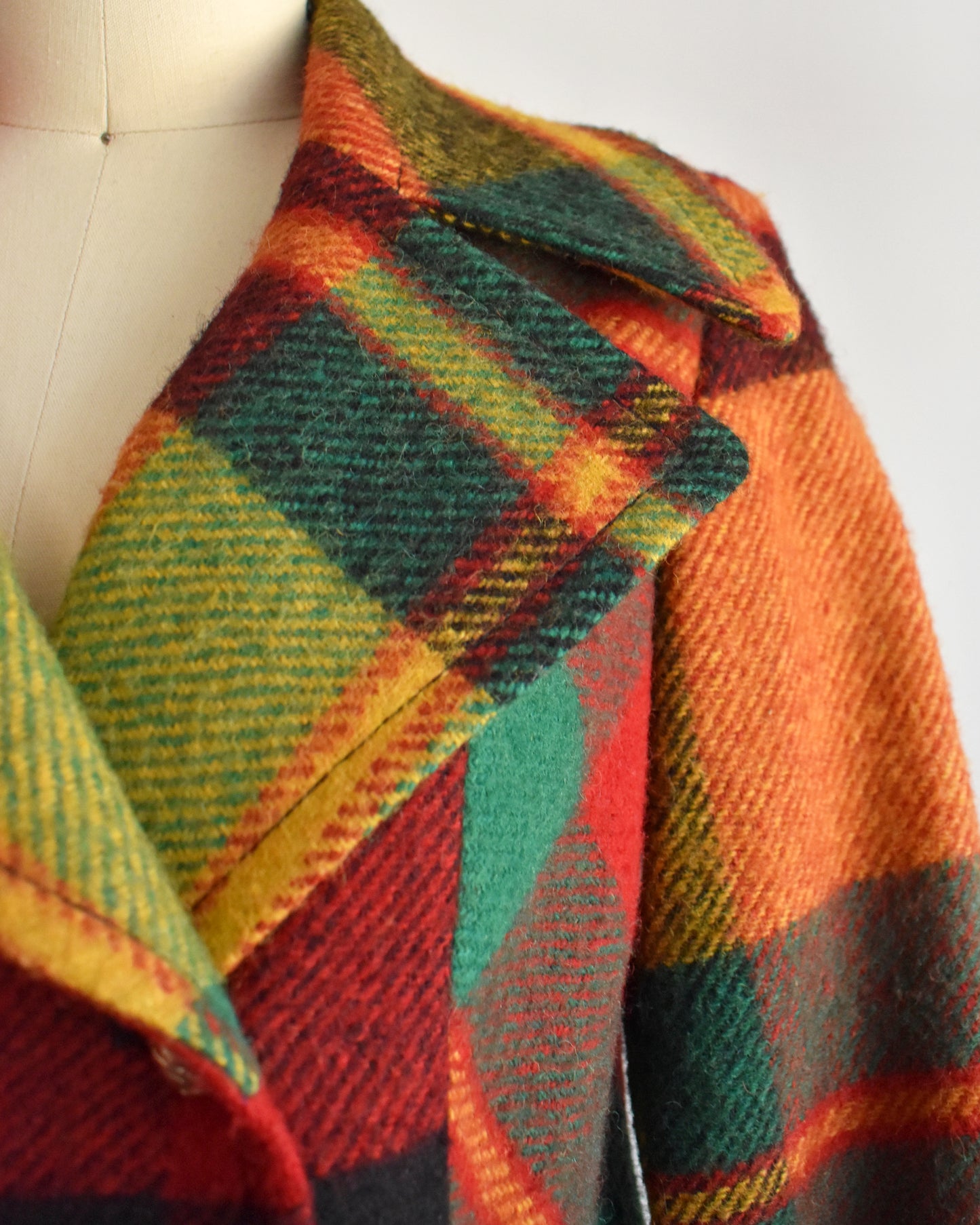 close up of the collar on a vintage 1970s rainbow plaid coat on a mannequin against a white background