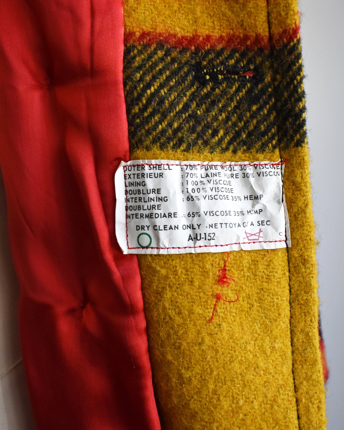 Close-up of a fabric label on a multicolored fabric with red, yellow, and black patterns.