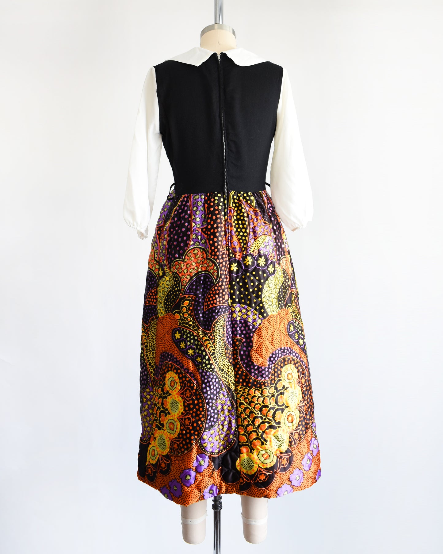 back view of a vintage 1970s psychedelic quilted maxi dress on a mannequin against a white background