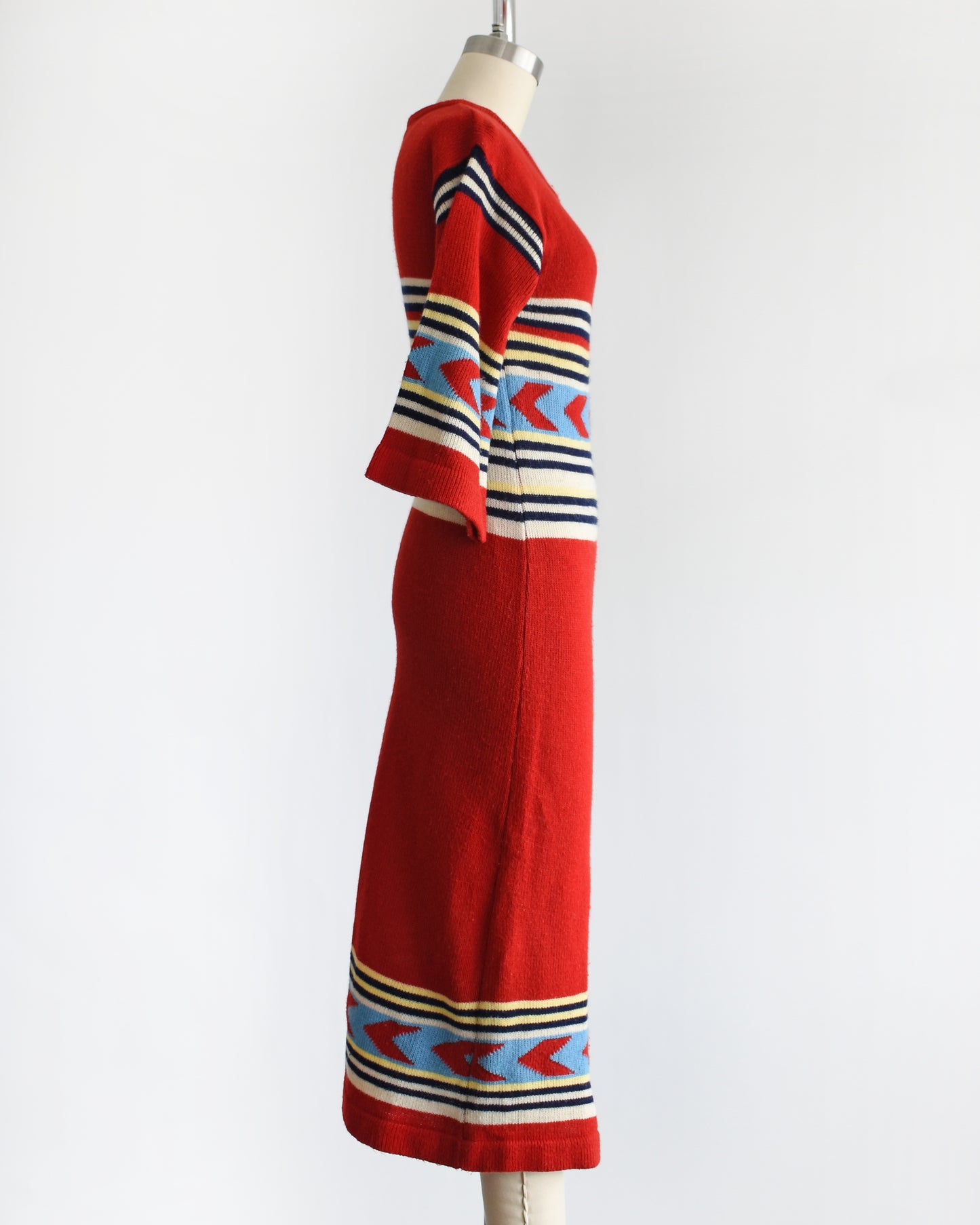 side view of a vintage 1970s southwestern red sweater dress with a patterned bodice on a mannequin against a white background