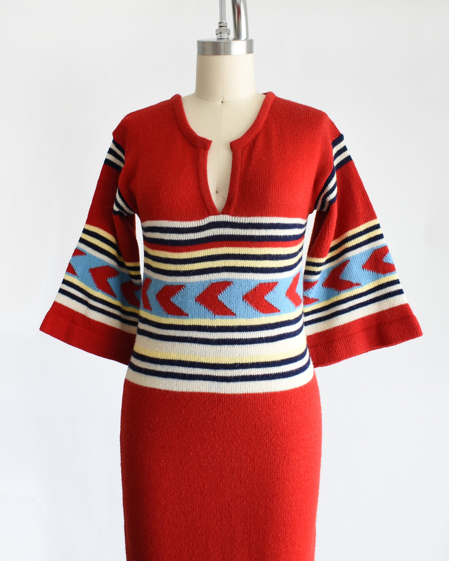 side front view of a vintage 1970s southwestern red sweater dress with a patterned bodice on a mannequin against a white background