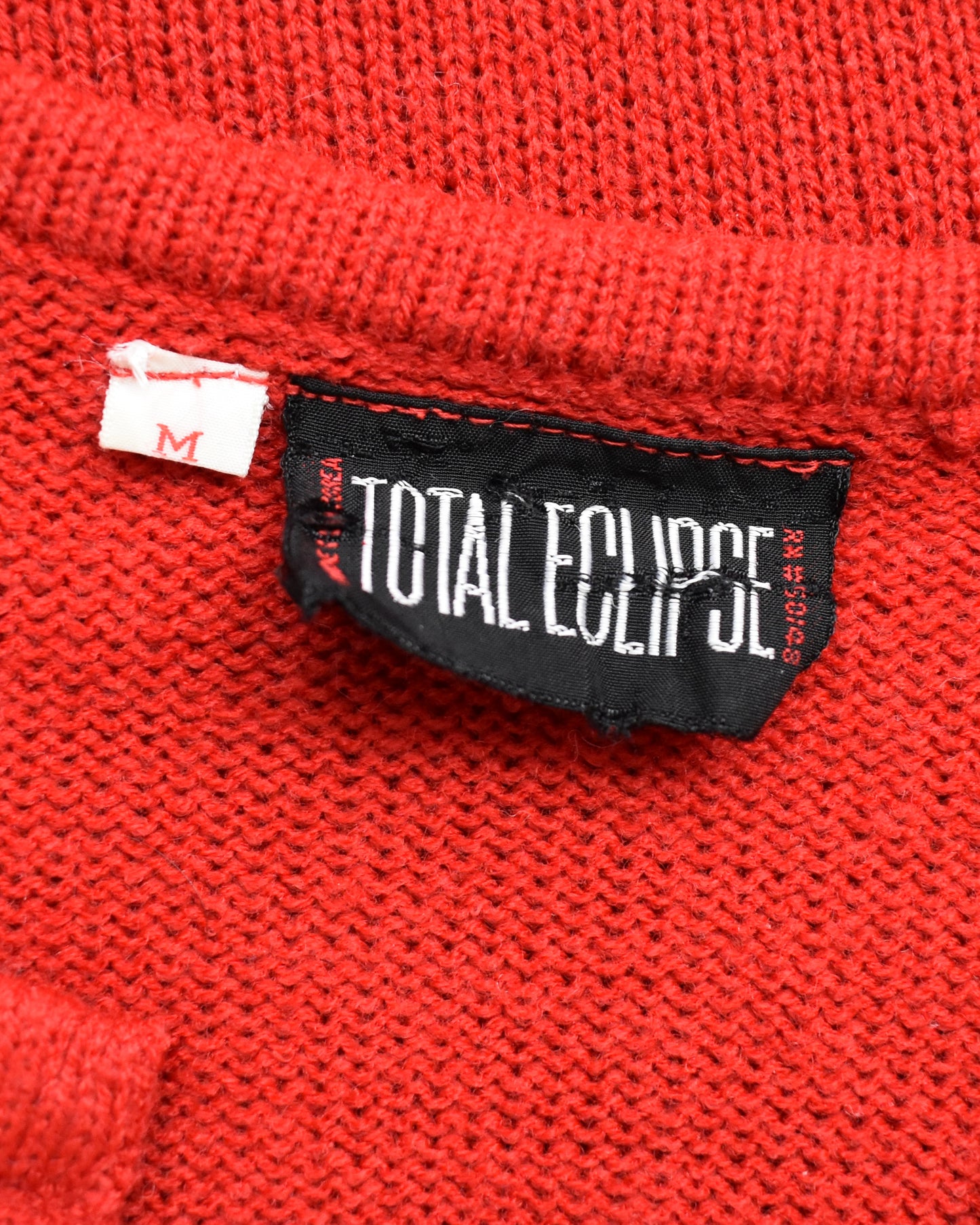 Close-up of a red fabric with a 'Total Eclipse' label on a textured background