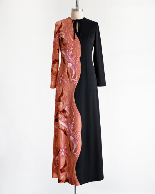 a vintage 1970s dress that has a pink waves and birds on one side and sold black on the other on a mannequin against a white background