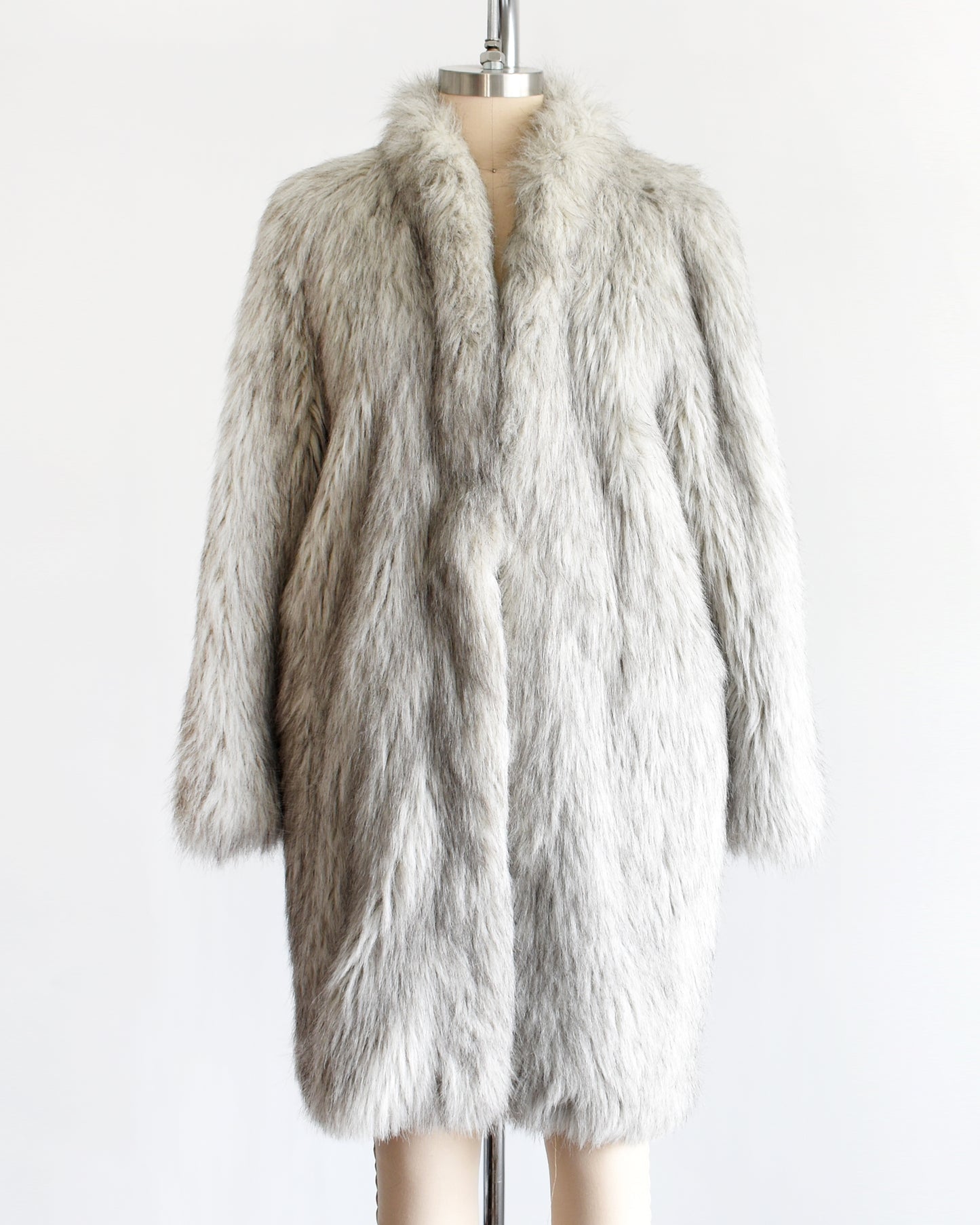 a vintage 1980s faux fur silver fox coat on a dress form on a white background