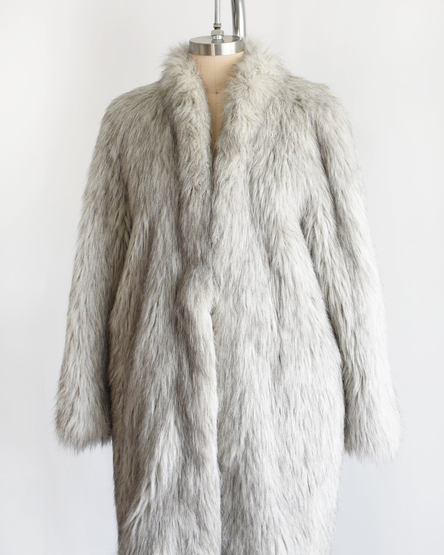 side front view of a vintage 1980s faux fur silver fox coat on a dress form on a white background