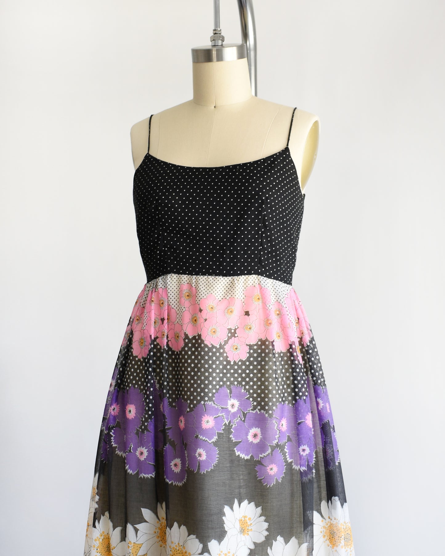 side front view of a vintage 1970s black floral dress on a mannequin against a white background