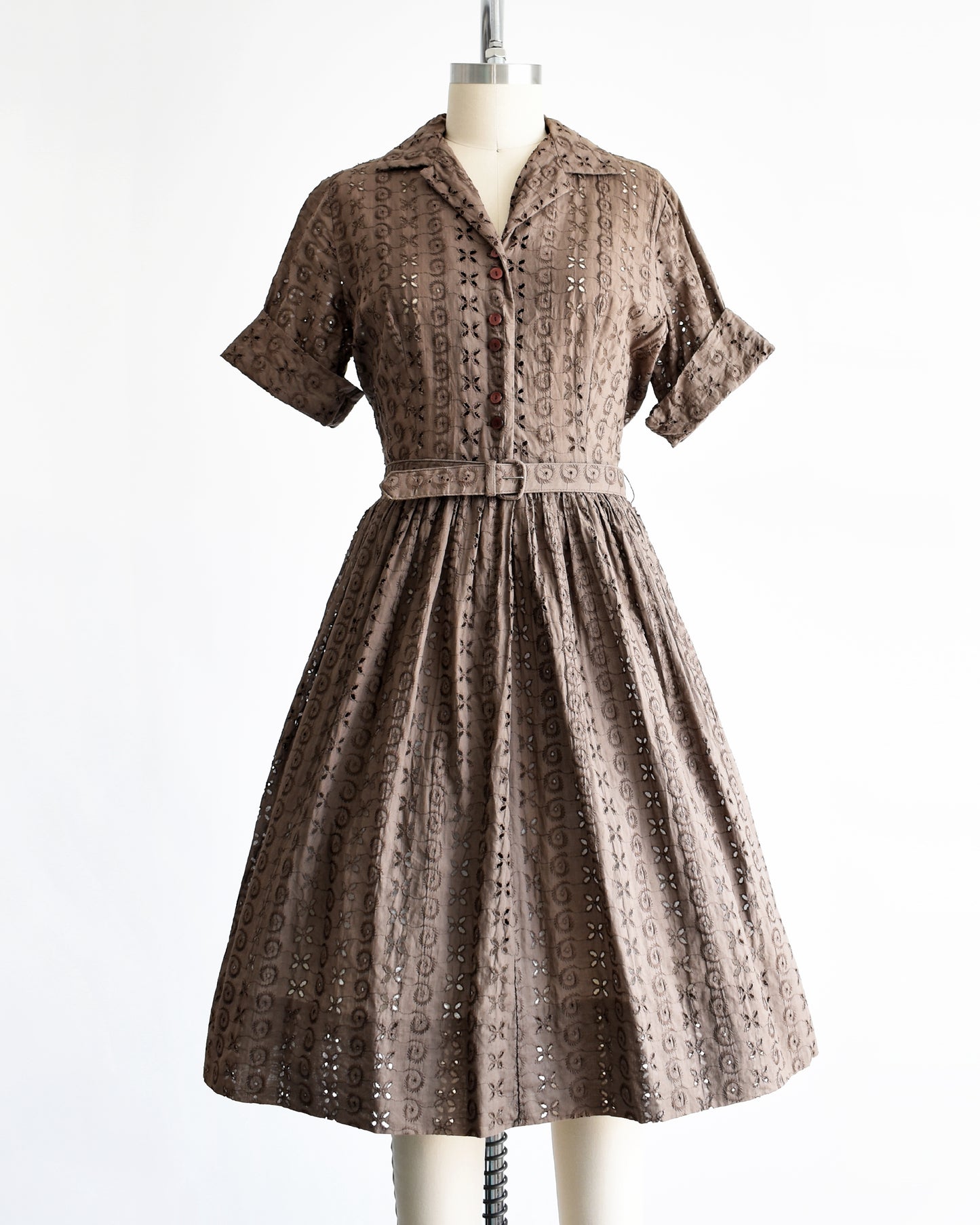 a vintage 1950s brown eyelet shirt dress with belt on a dress form