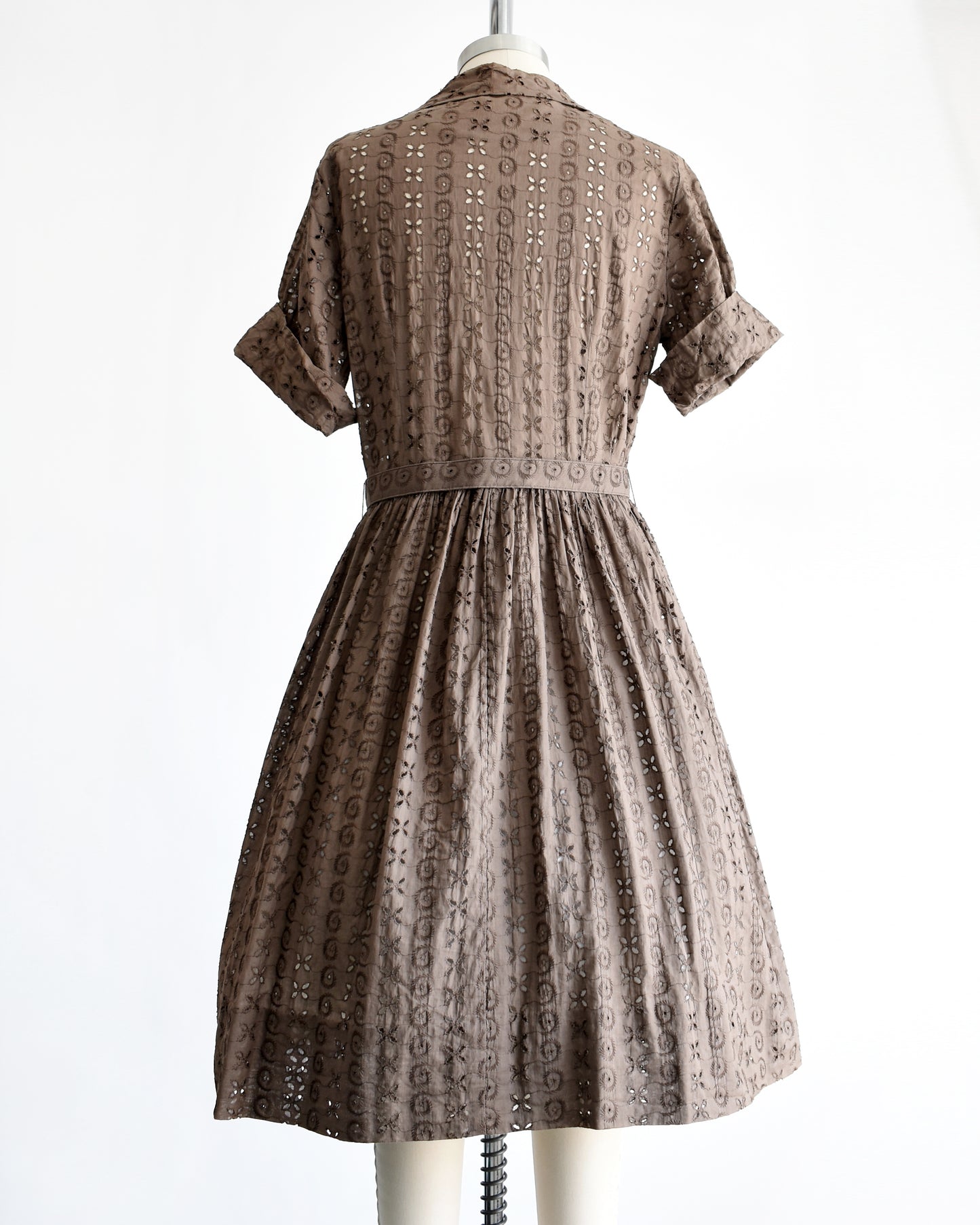back view of a vintage 1950s brown eyelet shirt dress with belt on a dress form