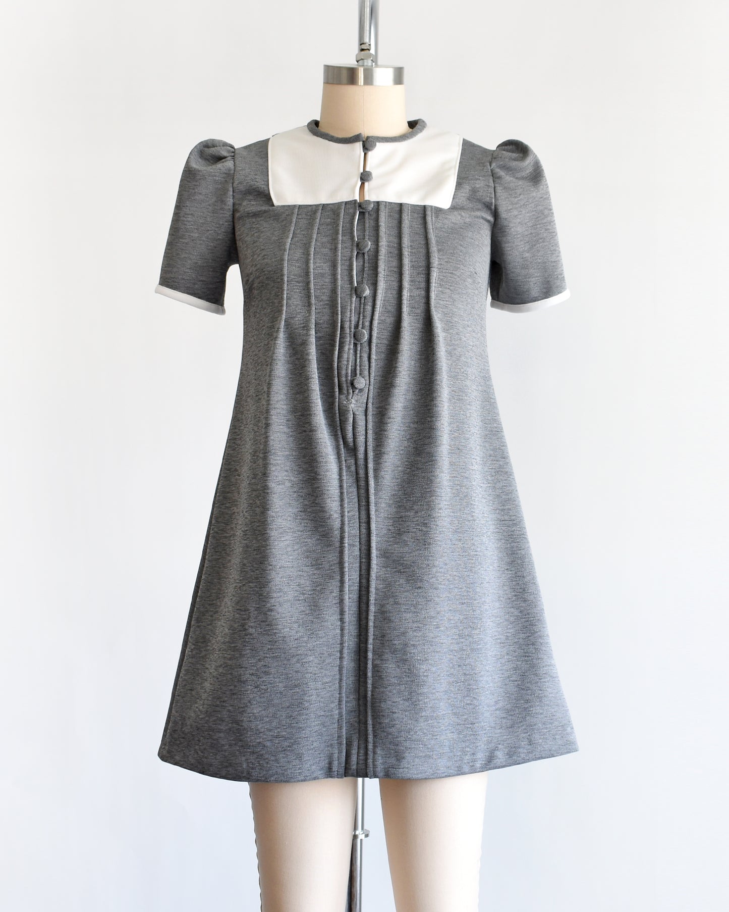 a vintage 1960s gray dress with white collar on a mannequin against a white background