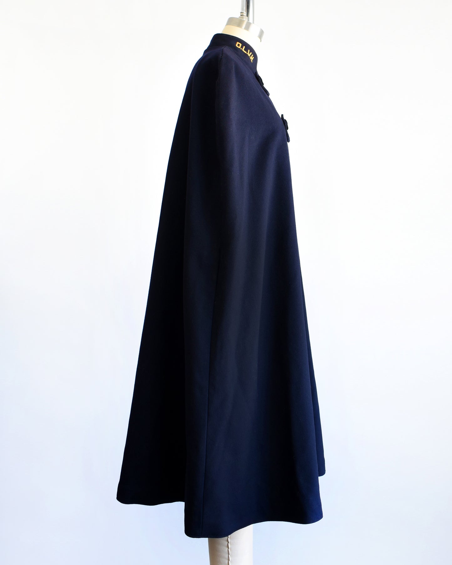 side view of a vintage 1940s navy nurse's cape on a mannequin against a white background.