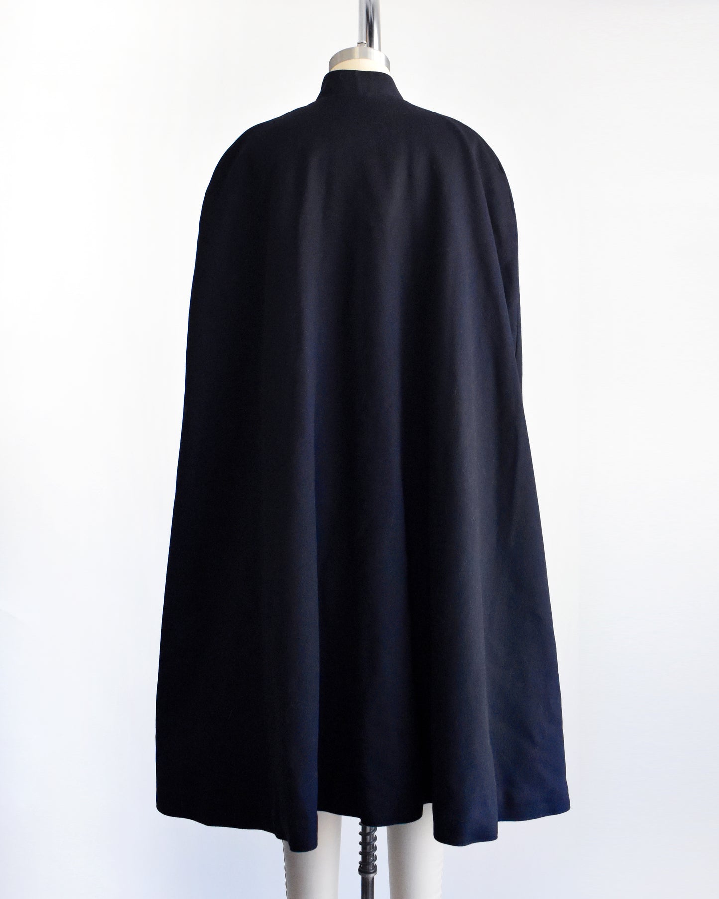 back view of a vintage 1940s navy nurse's cape on a mannequin against a white background.