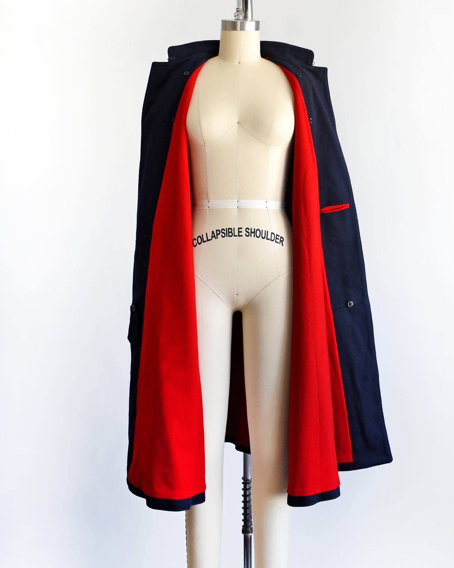 a vintage 1940s navy nurse's cape on a mannequin against a white background. the cape is open, showing the bight red wool lining.