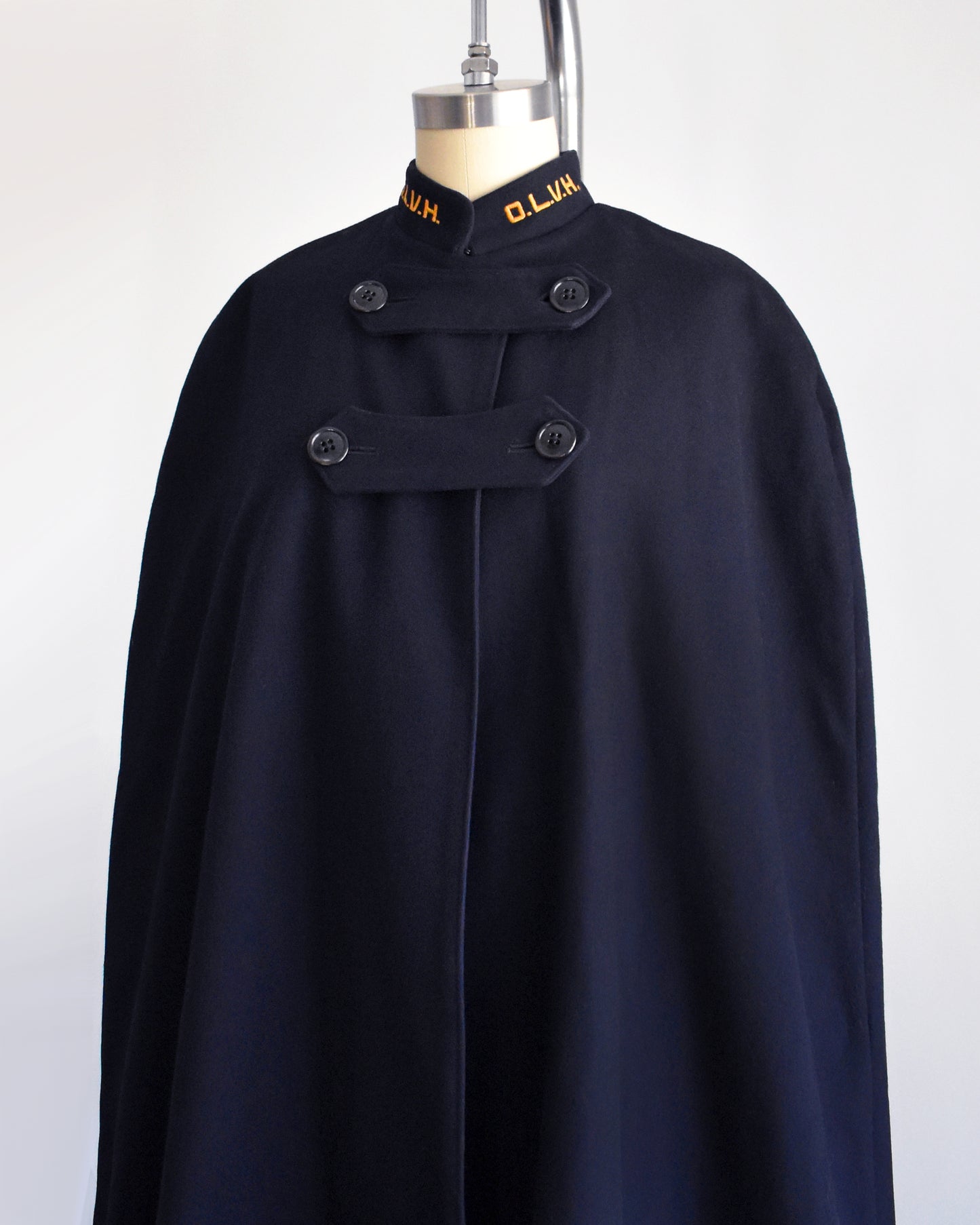 side view of a vintage 1940s navy nurse's cape on a mannequin against a white background.