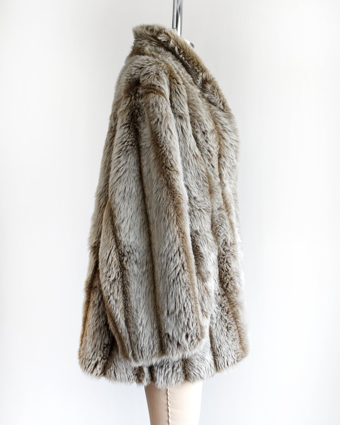 side view of a vintage 1980s brown and gray faux fur coat on a mannequin against a white background