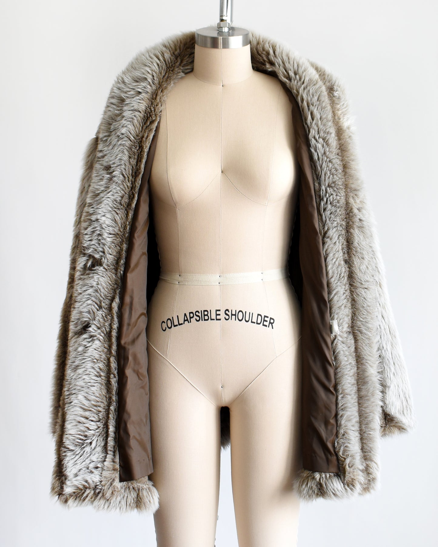 a vintage 1980s brown and gray faux fur coat on a mannequin against a white background. the coat is open on the mannequin