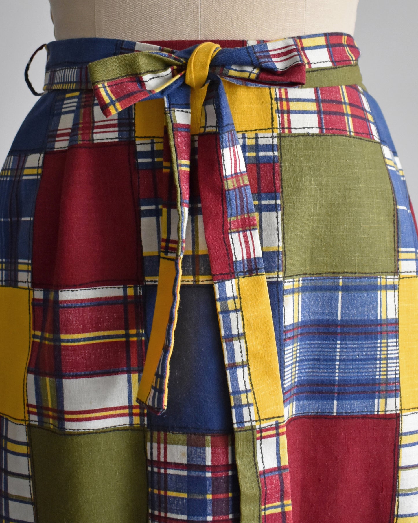close up of the waist of a a vintage 1970s patchwork madras plaid maxi skirt with matching tie belt