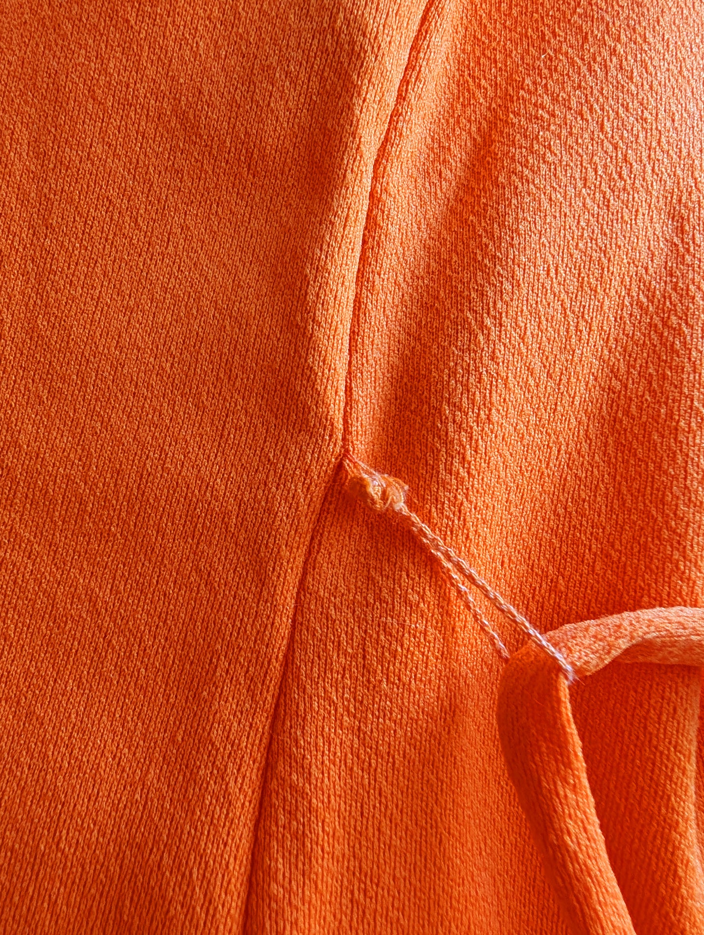 close up of the belt loop that is only holding on by some frayed threads.