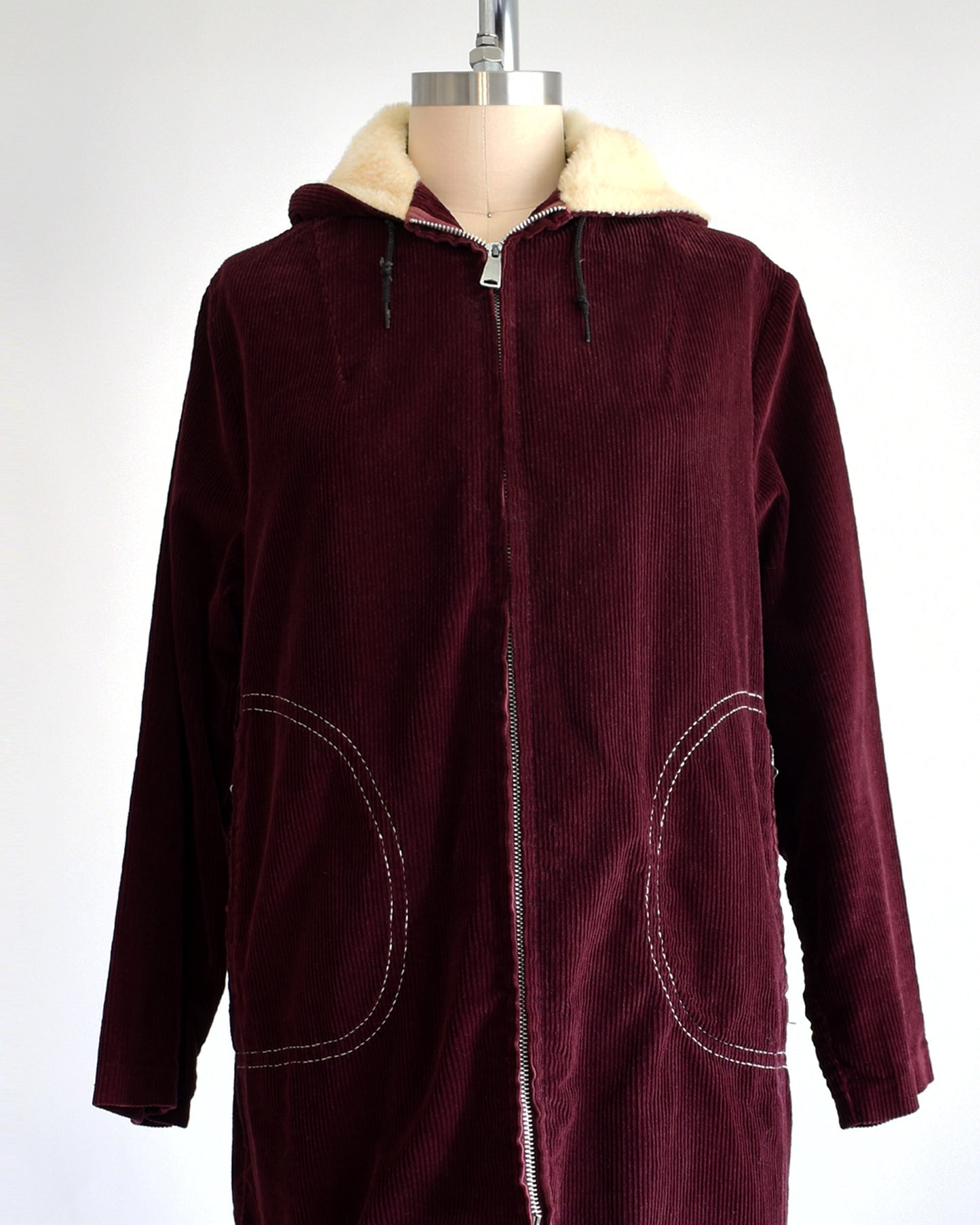 a vintage 1970s burgundy corduroy jacket with a sherpa lined hood on a dress form