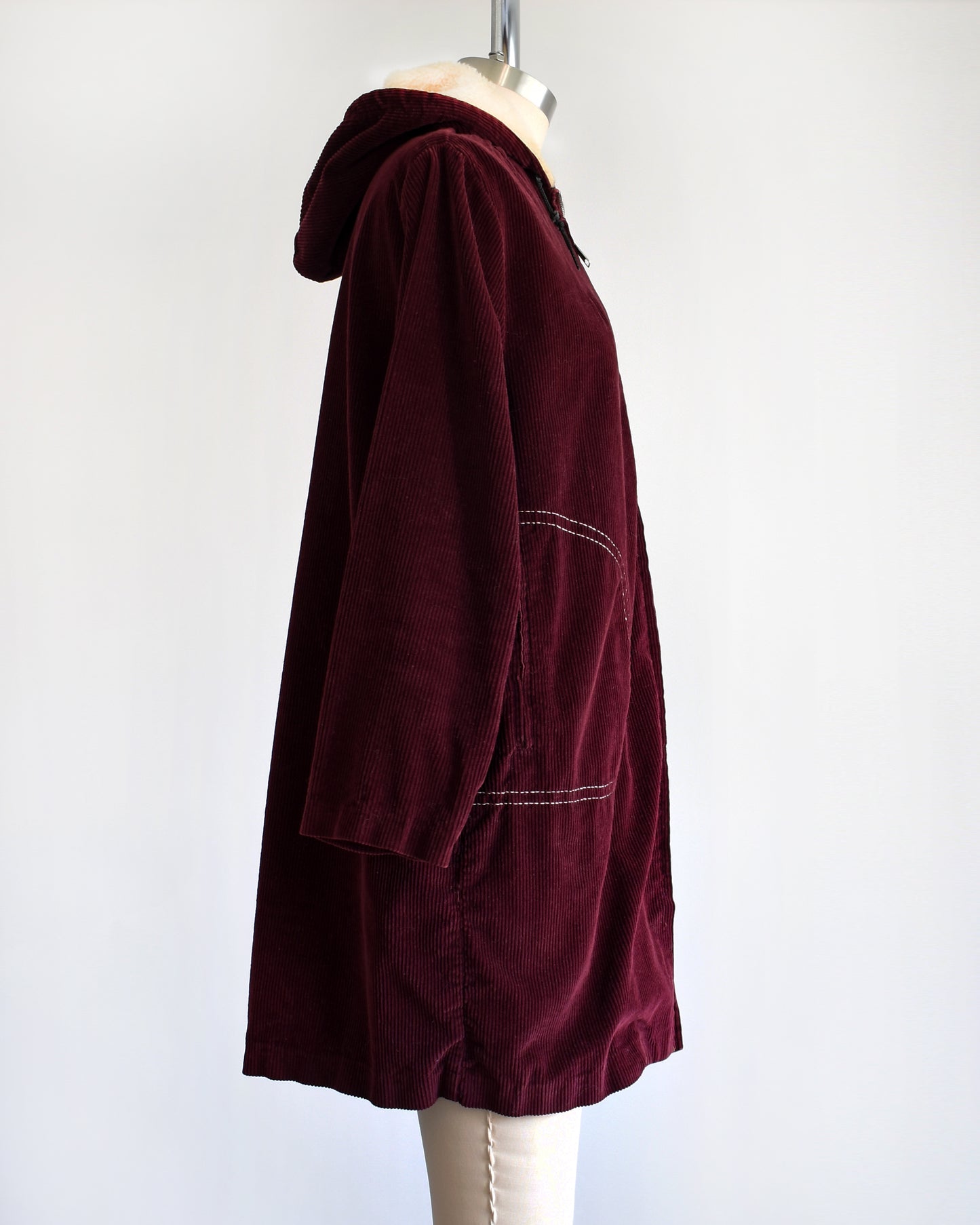 side view of a vintage 1970s burgundy corduroy jacket with a sherpa lined hood on a dress form