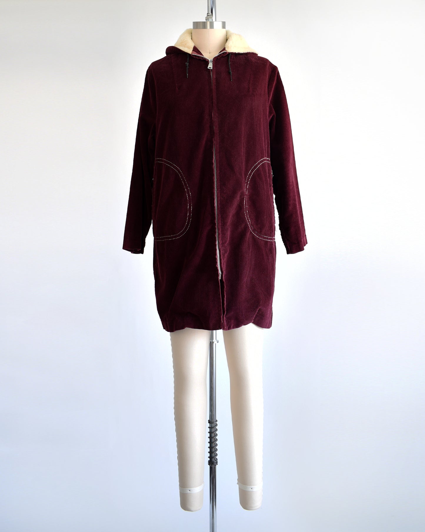 a vintage 1970s burgundy corduroy jacket with a sherpa lined hood on a dress form