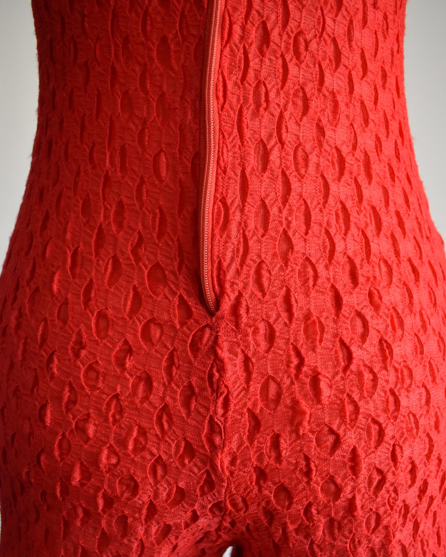 close up of the back zipper which doesn't lie straight or flat on the back. there's also some visible stitching below the zipper.