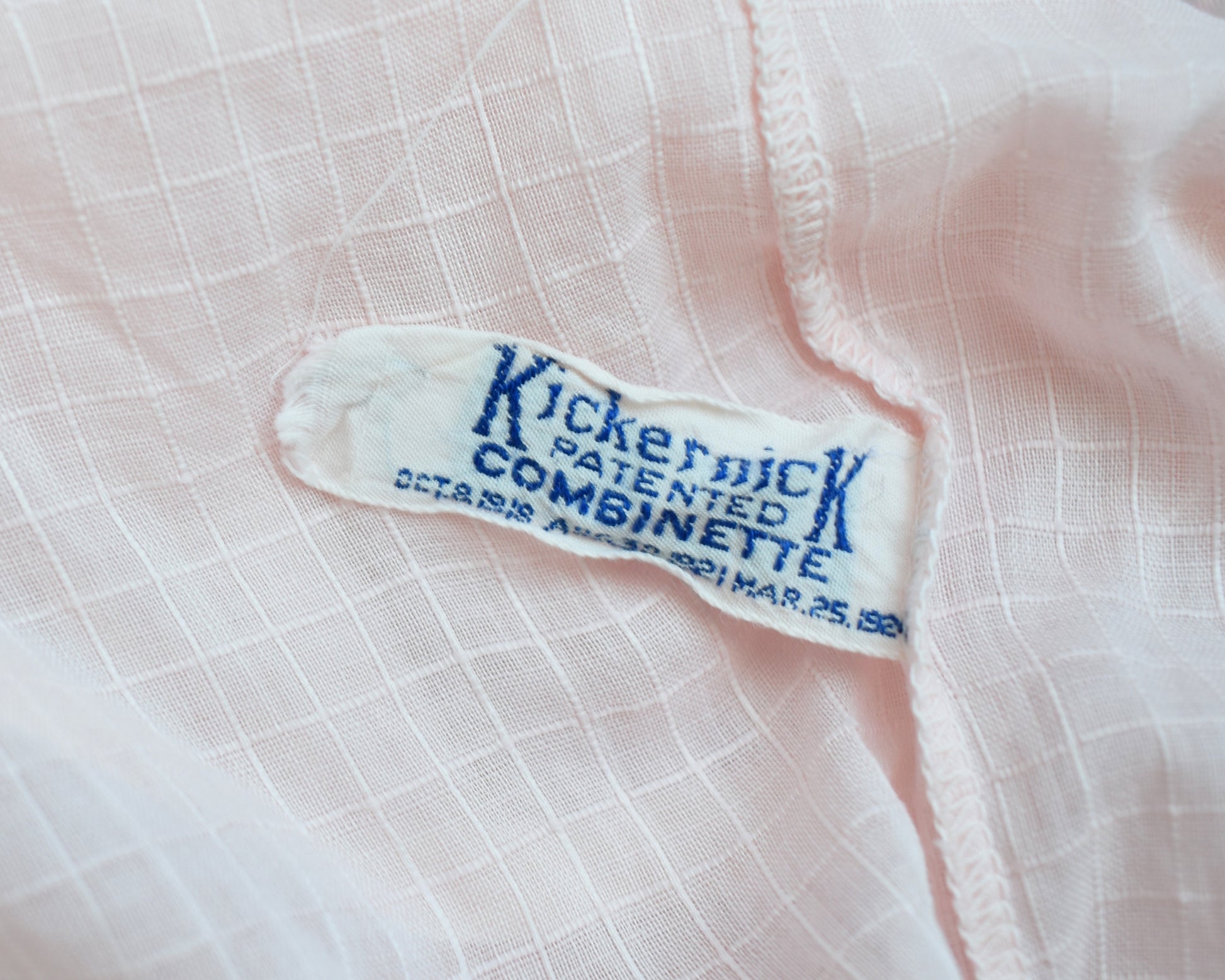 Close up of the tag that says Kickernick Patented Combinette Oct 8 1918 Aug 30 1921 Mar 25 1924