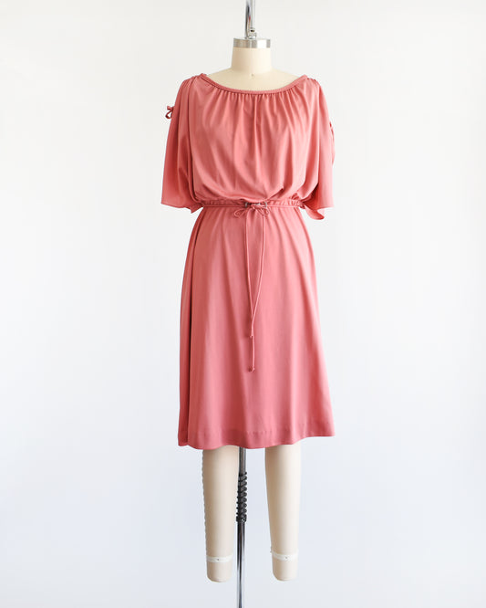 Pretty vintage 1970s dusty pink dress with a blouson bodice and slit flutter sleeves that drawstrings at the end so you can adjust the length. Matching tie belt around the waist with a silver accent in the middle of the waist.