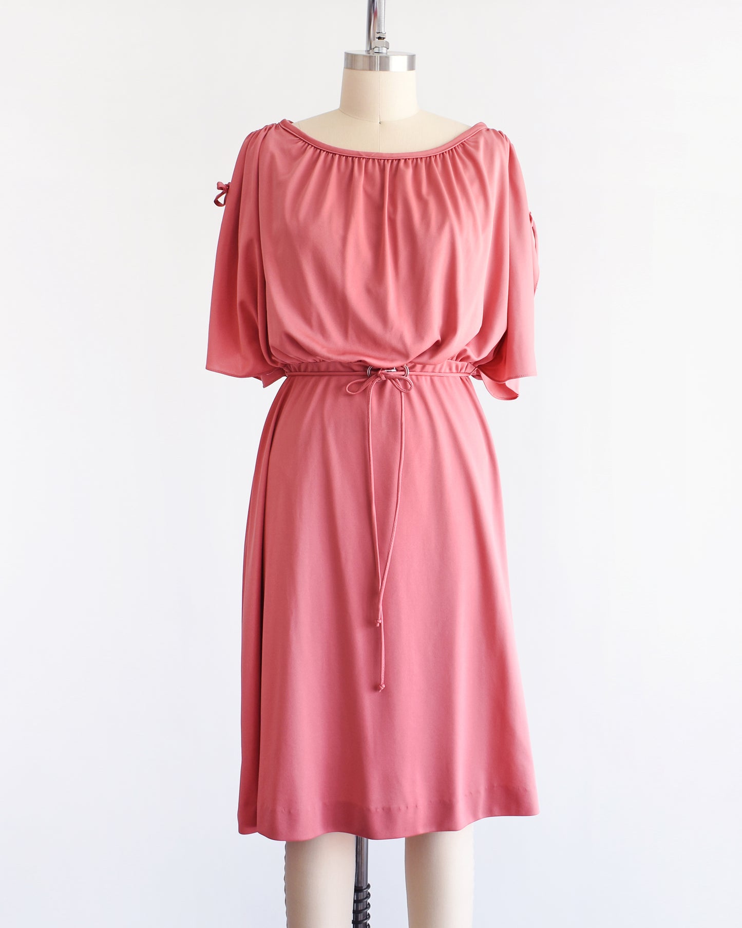 Pretty vintage 1970s dusty pink dress with a blouson bodice and slit flutter sleeves that drawstrings at the end so you can adjust the length. Matching tie belt around the waist with a silver accent in the middle of the waist.