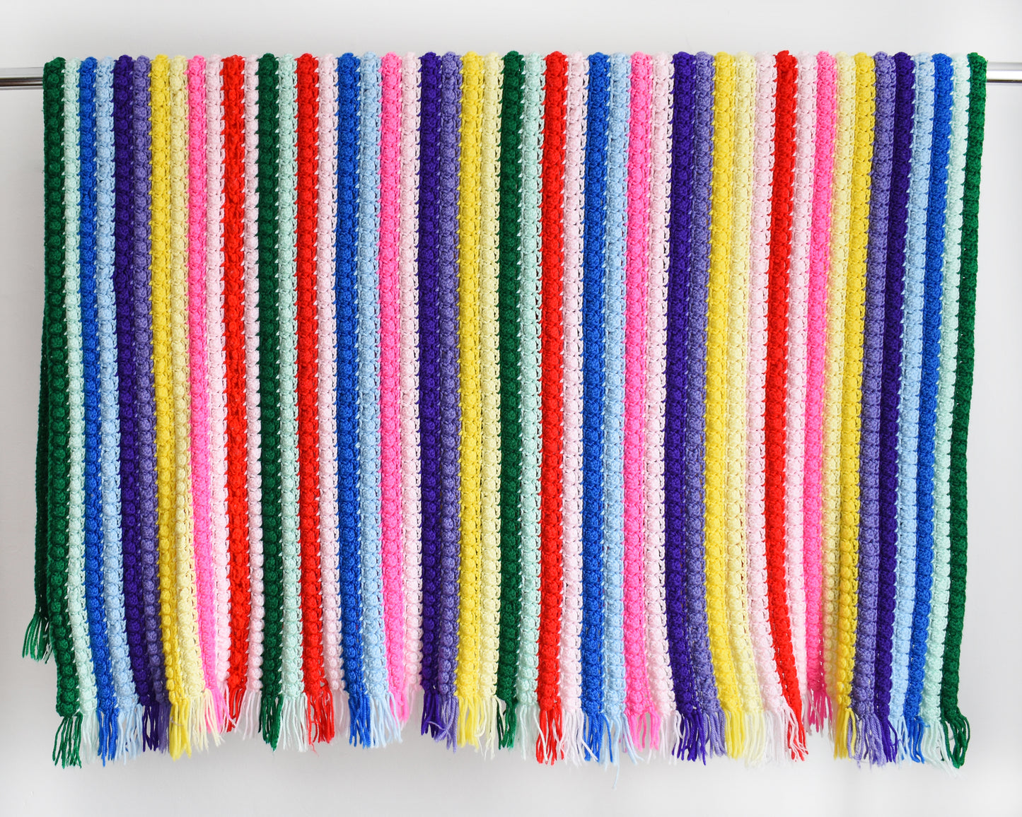 a vintage rainbow striped blanket draped over a silver rod
