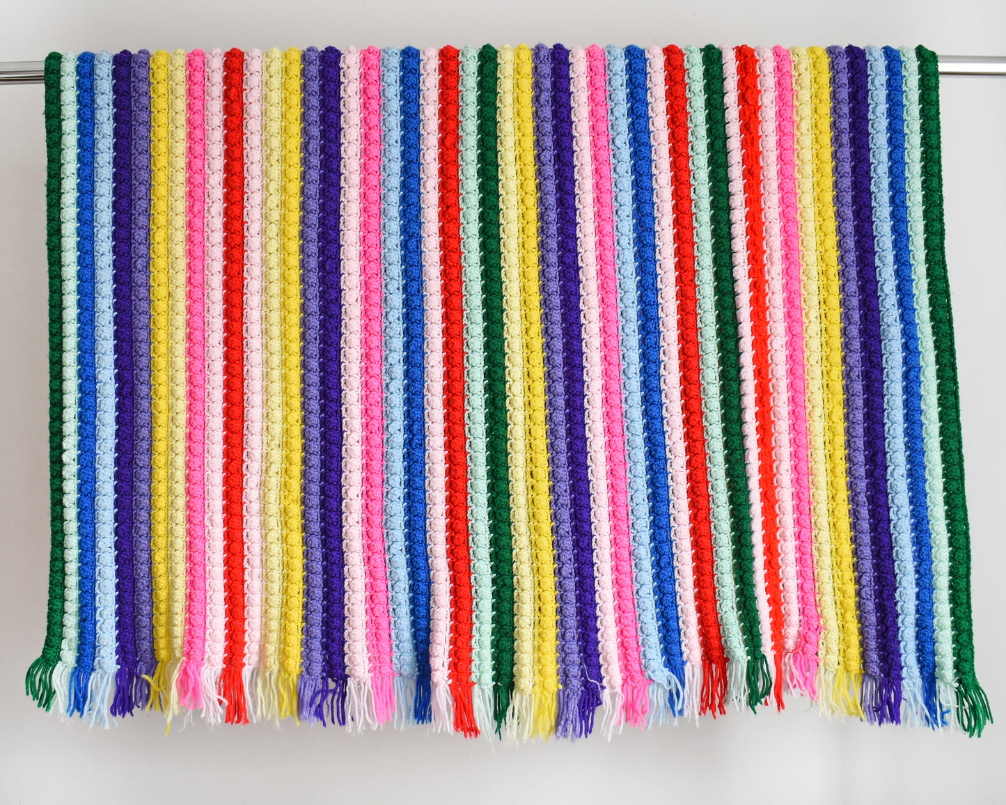 a vintage rainbow striped blanket draped over a silver rod