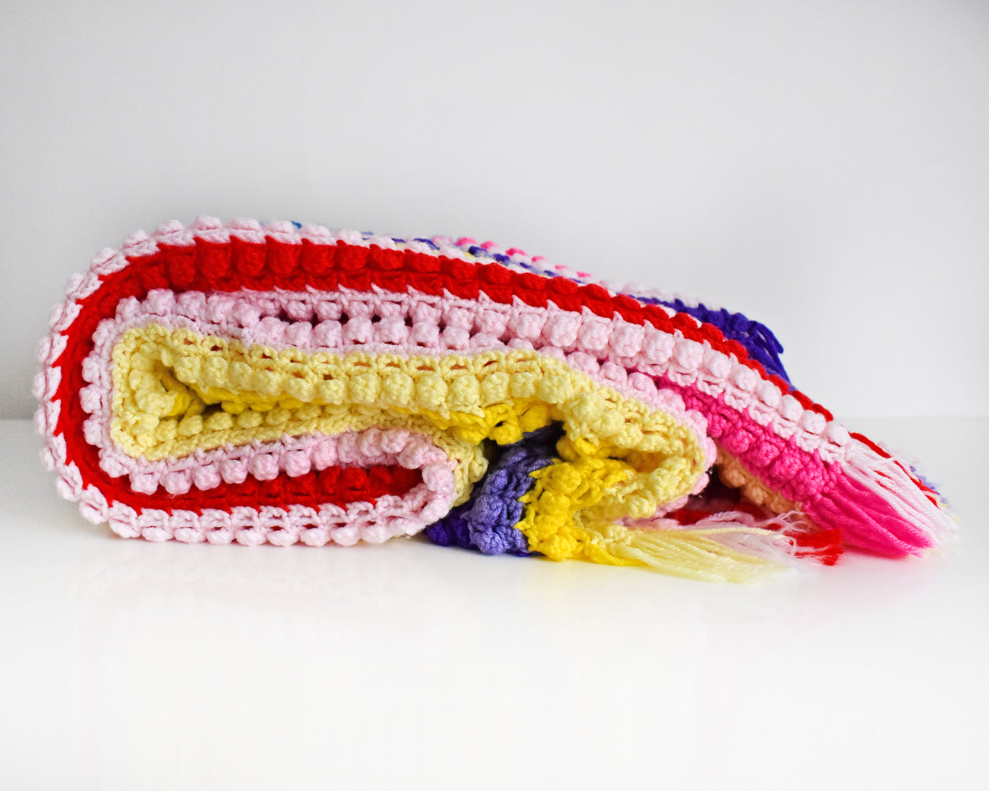 a vintage rainbow striped blanket folded on a white table