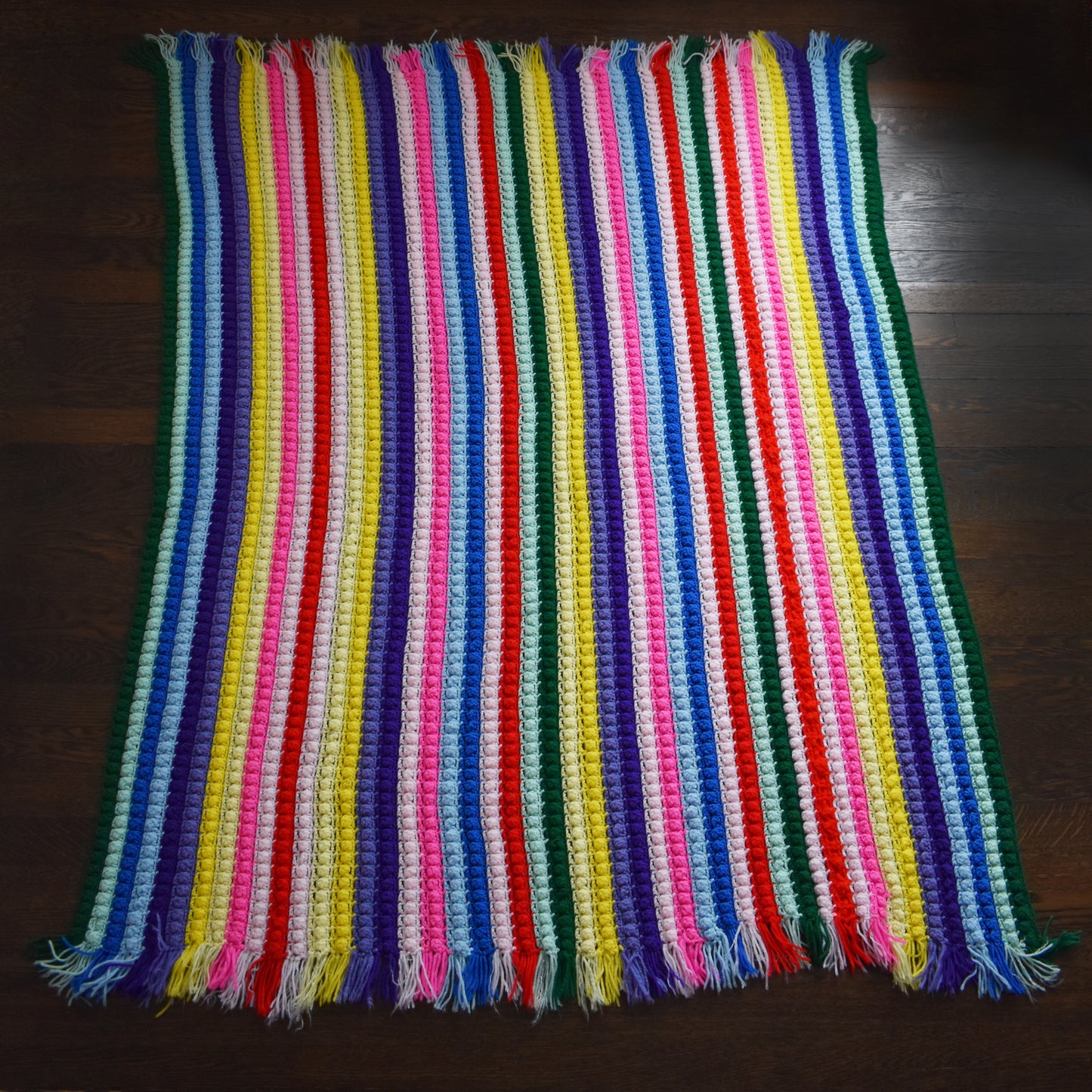 a vintage rainbow striped blanket laid out on a wood floor