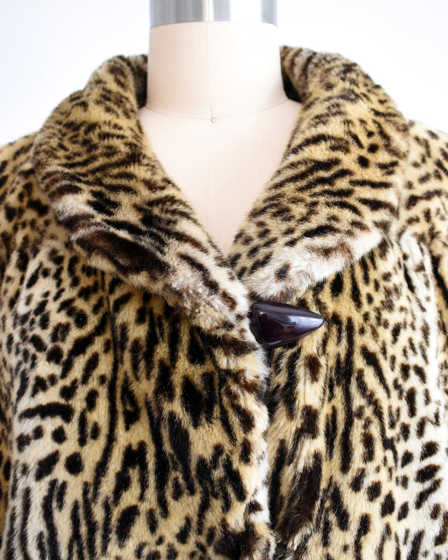 close up of the large brown button on a vintage 1970s faux fur leopard print coat
