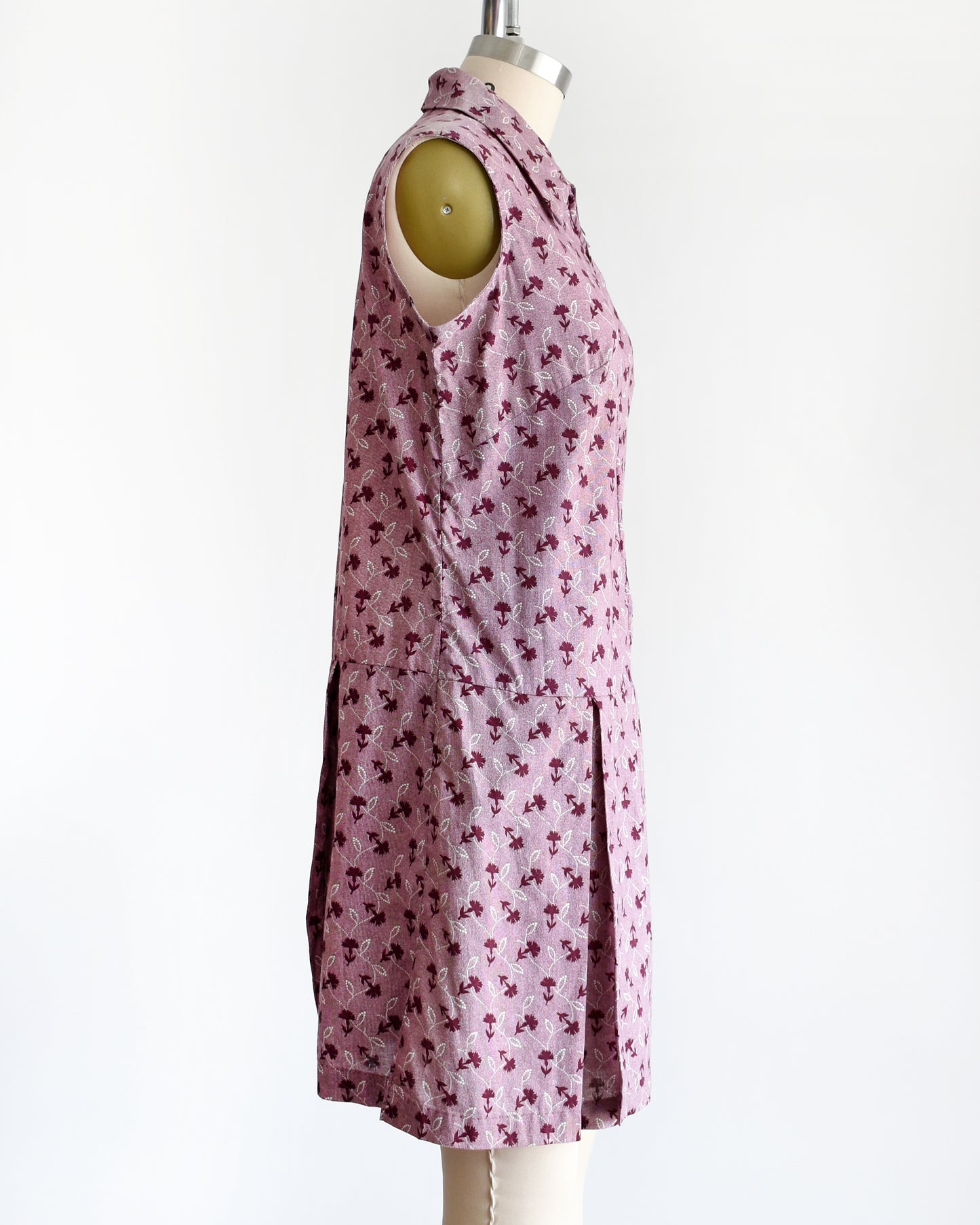 Side view of a 1970s vintage romper features a cute purple and white floral print, a collared neckline, and a metal zipper closure down the front.