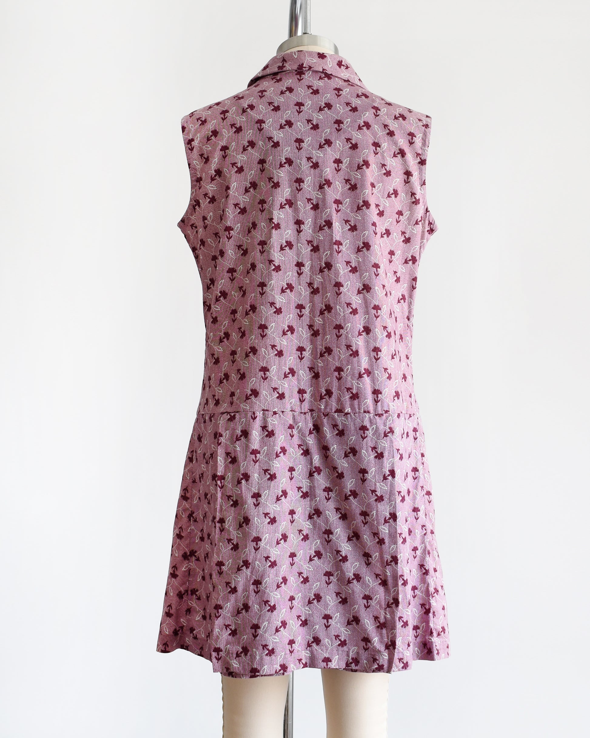 Back view of a Side view of a 1970s vintage romper features a cute purple and white floral print and collared neckline