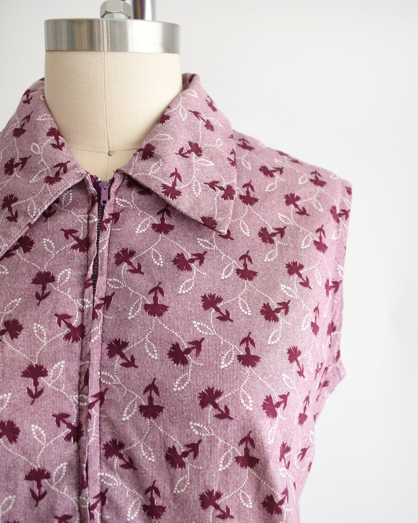 Close up of the collared neckline, floral print, and metal zipper